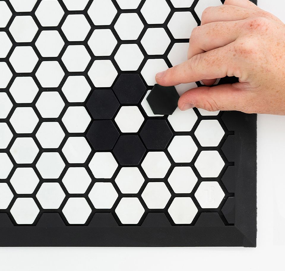 Someone placing a tile on a tile mat.