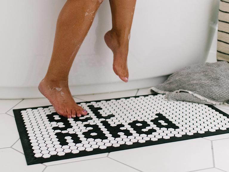 Person stepping out of bath onto tile mat