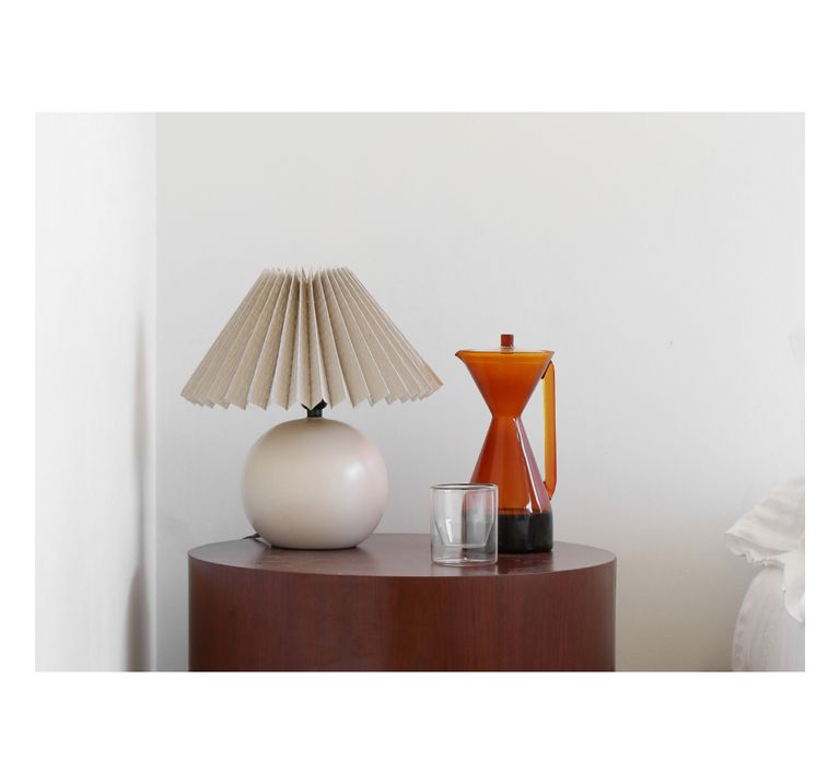 An Amber Pour Over Carafe next to a bed on a table.