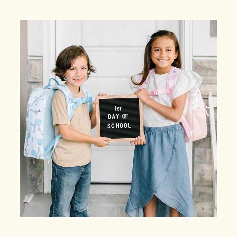 Two kids holding a letter board on their first day of school.