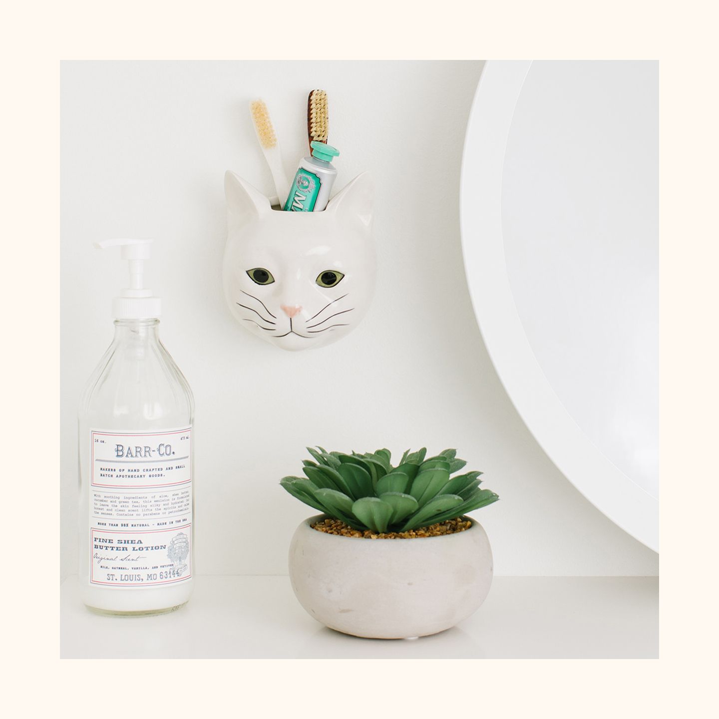 A cat ceramic wall vase holding a toothbrush and toothpaste.