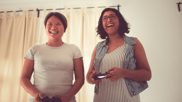 Photo of Adrianna and Sabrena playing Overcooked on a PS4 together