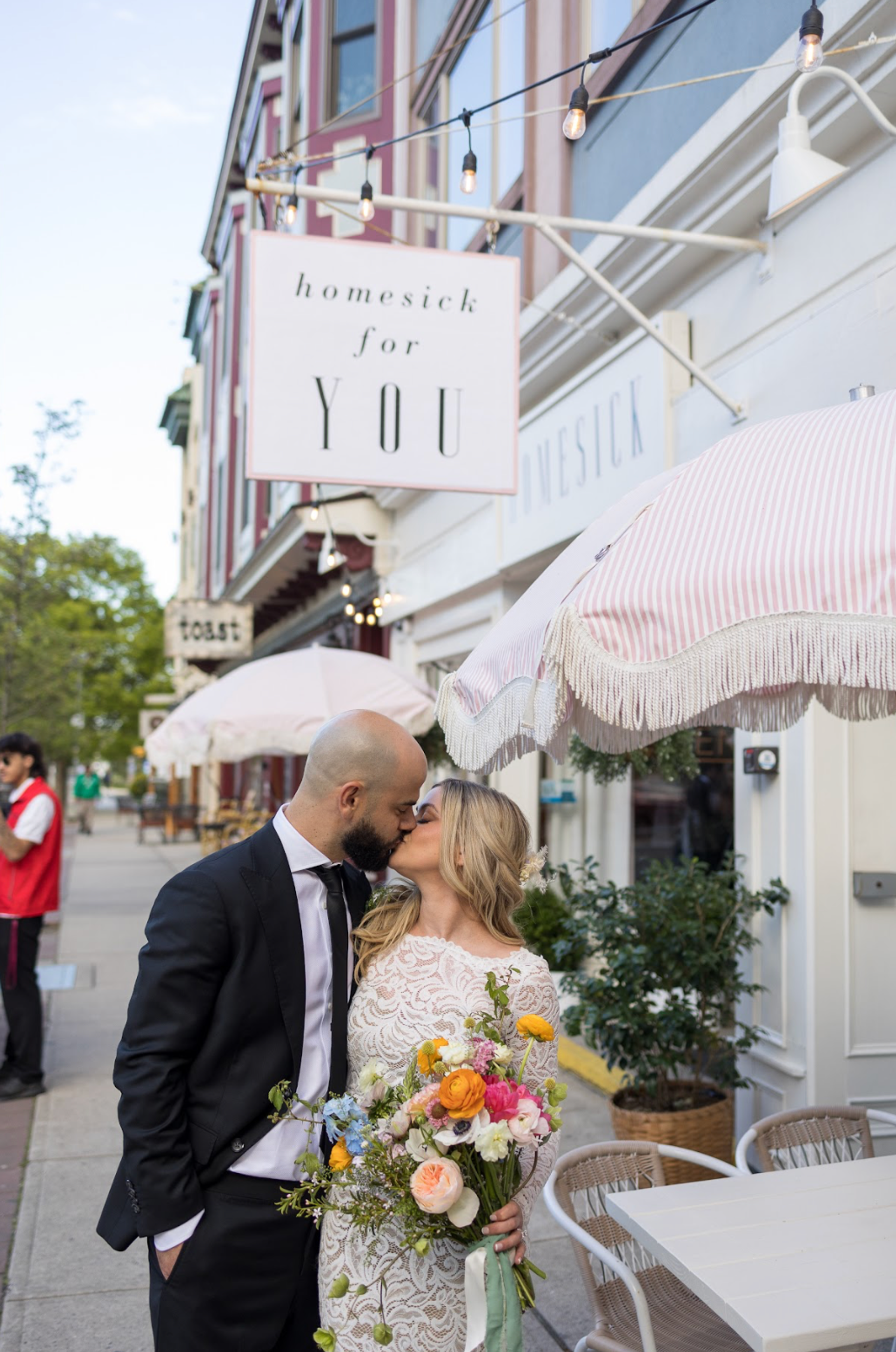 Photo of wedding couple kissing under Homesick sign
