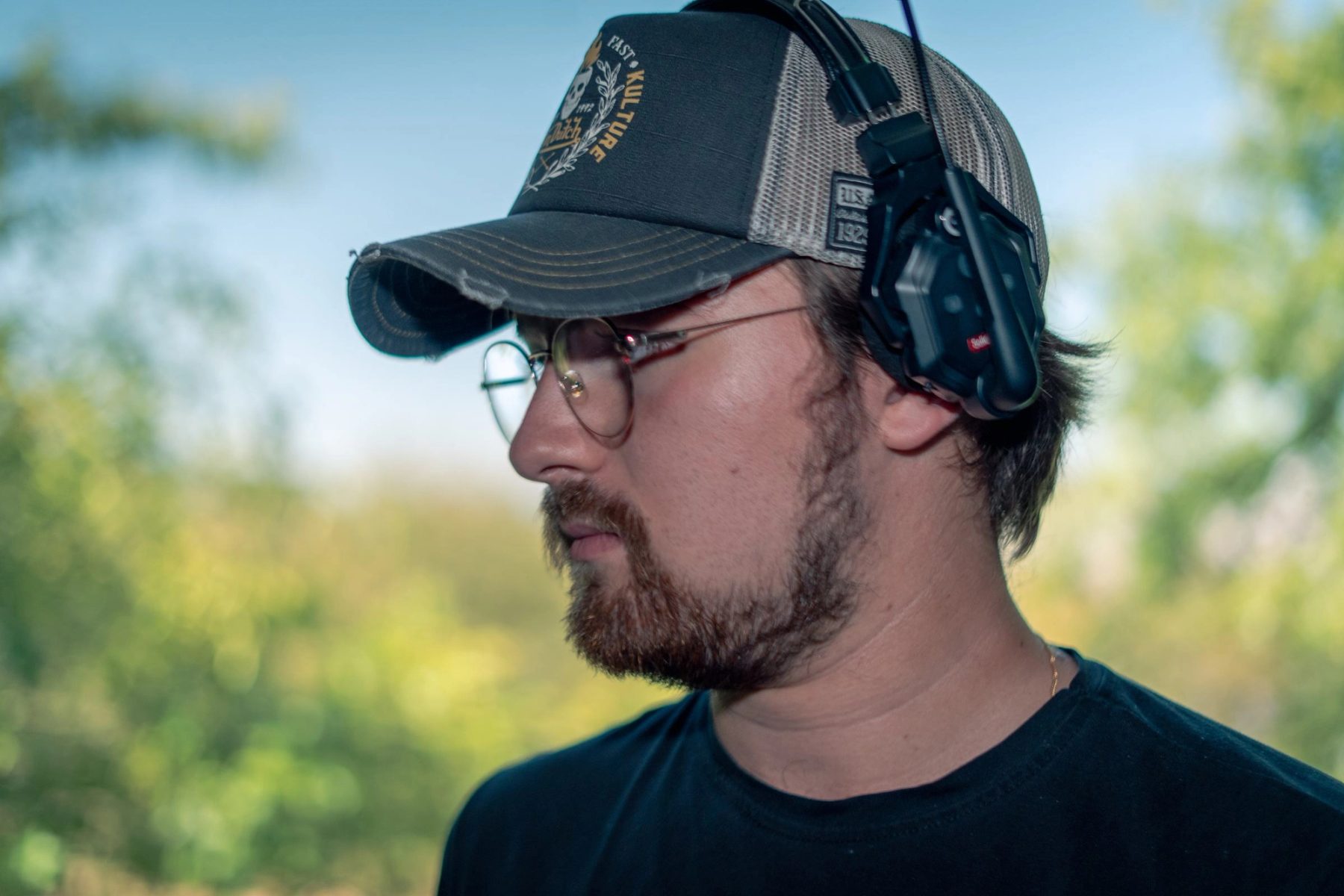 Portrait de profil d'un membre de l'equipe, casquette et casque de liaison, en exterieur