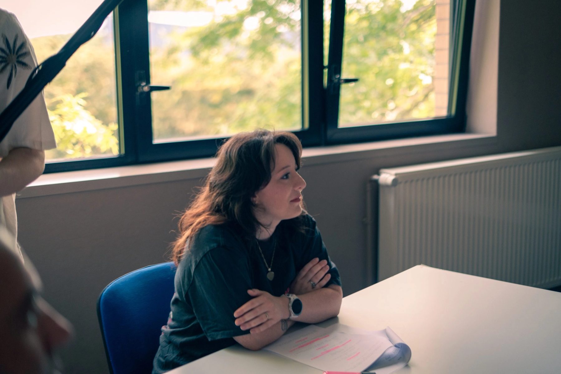 Entretien filme, une femme assise a une table dans la lumiere d une fenetre