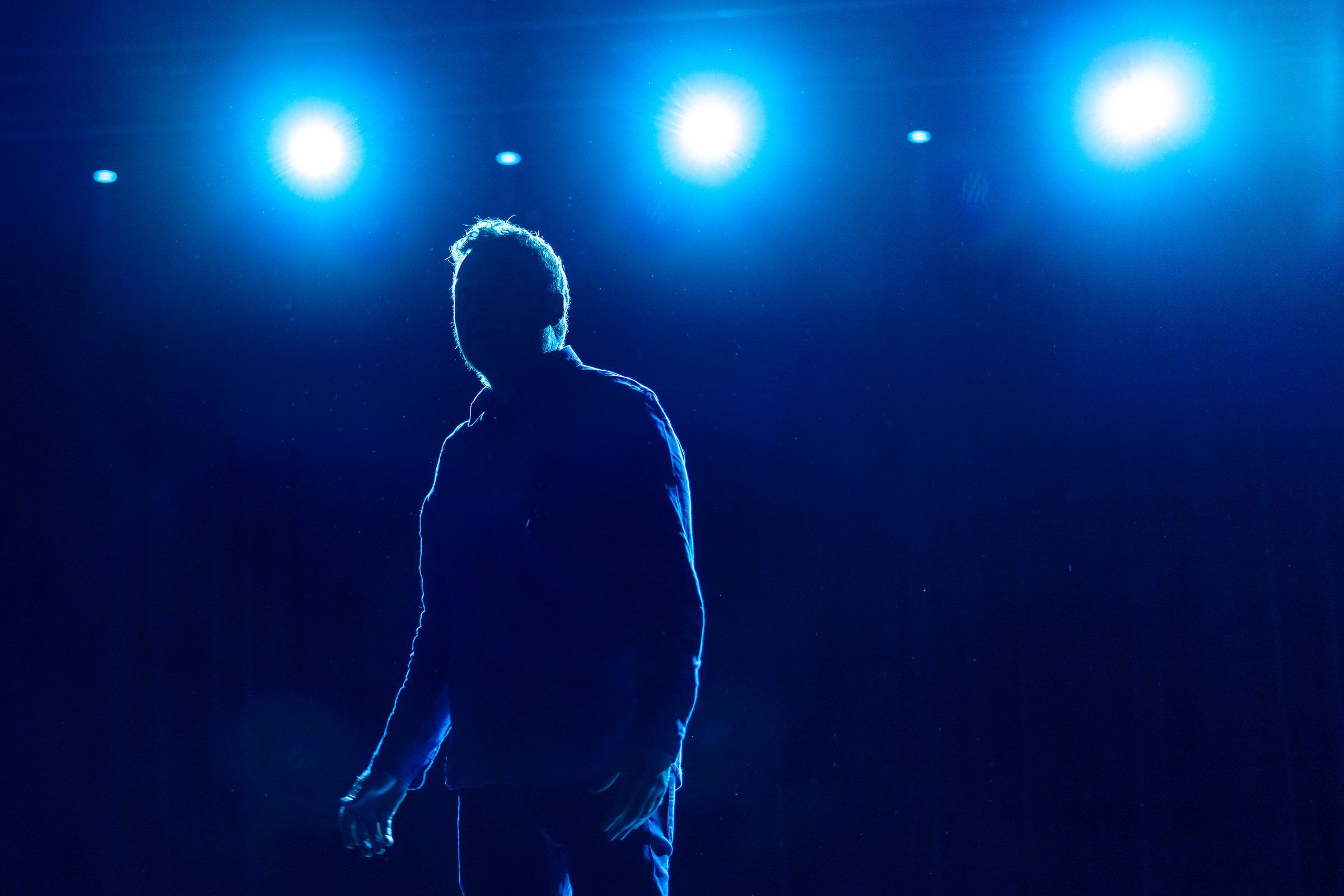 Silhouette a contre-jour de trois projecteurs, seule sur un plateau de theatre