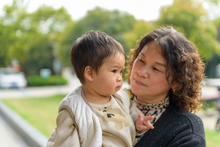 A woman holds a toddler outdoors