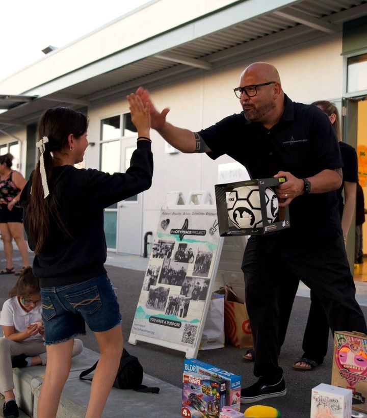 A City Peace Project staff member high-fives a student outside a school.