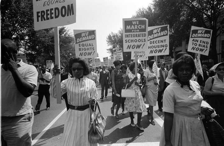 Women march carrying signs that read We Demand Equal Rights Now at the 1963 March on Washington