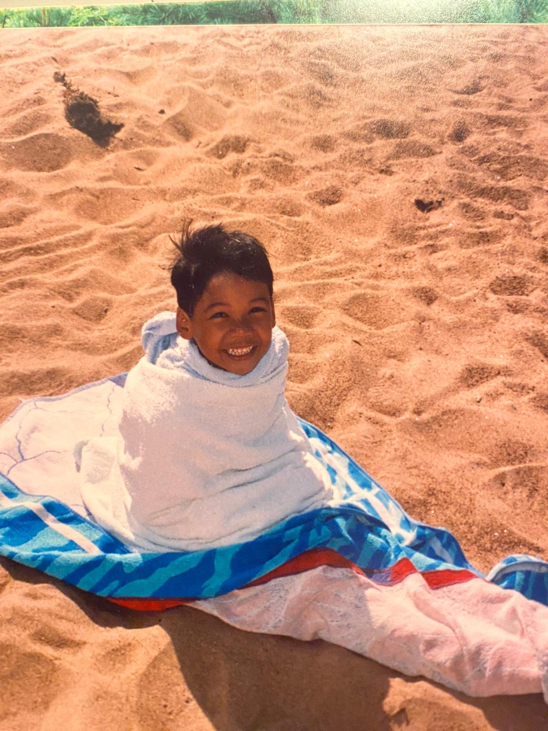 A photo of Don Hämäläinen as a child on the beach, wrapped in a towel.