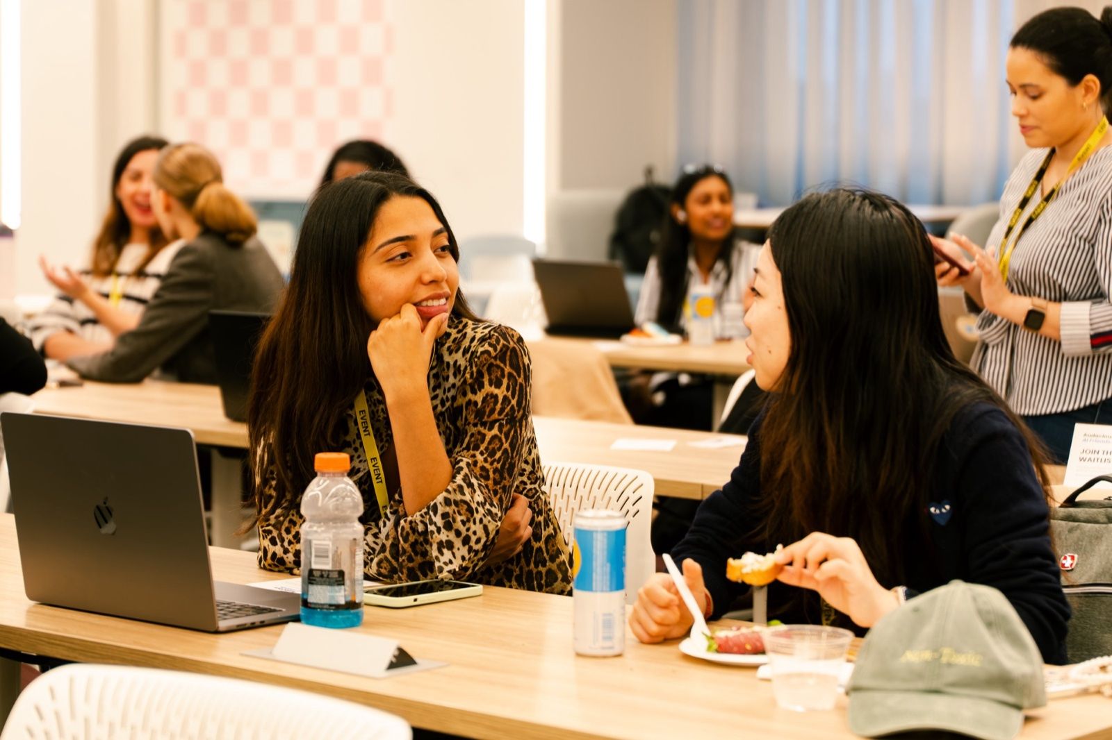 Two attendees talking over laptops and snacks