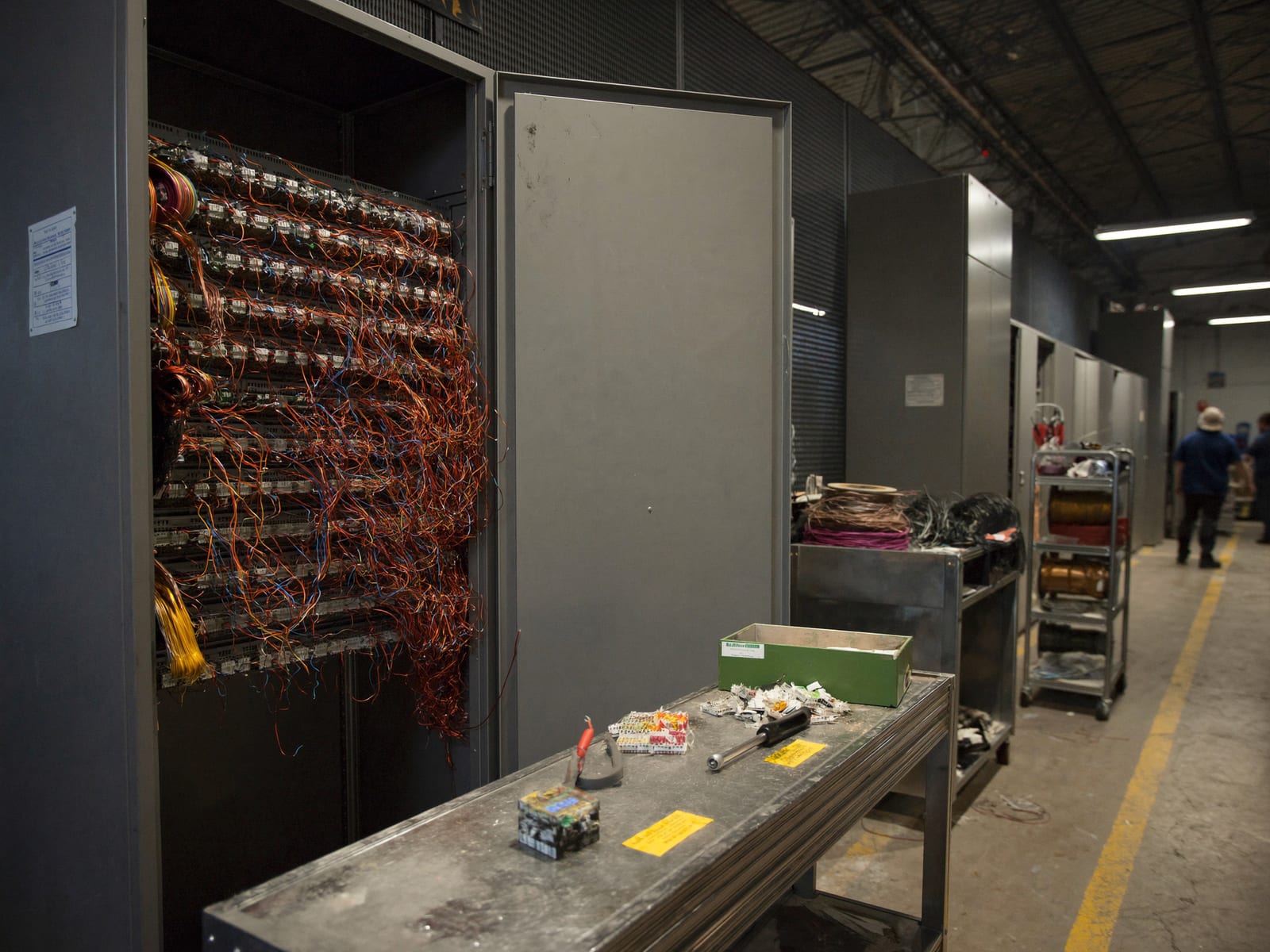 An electrical fabrication shop: switchgear enclosures open for wiring, terminal blocks and tools on a workbench