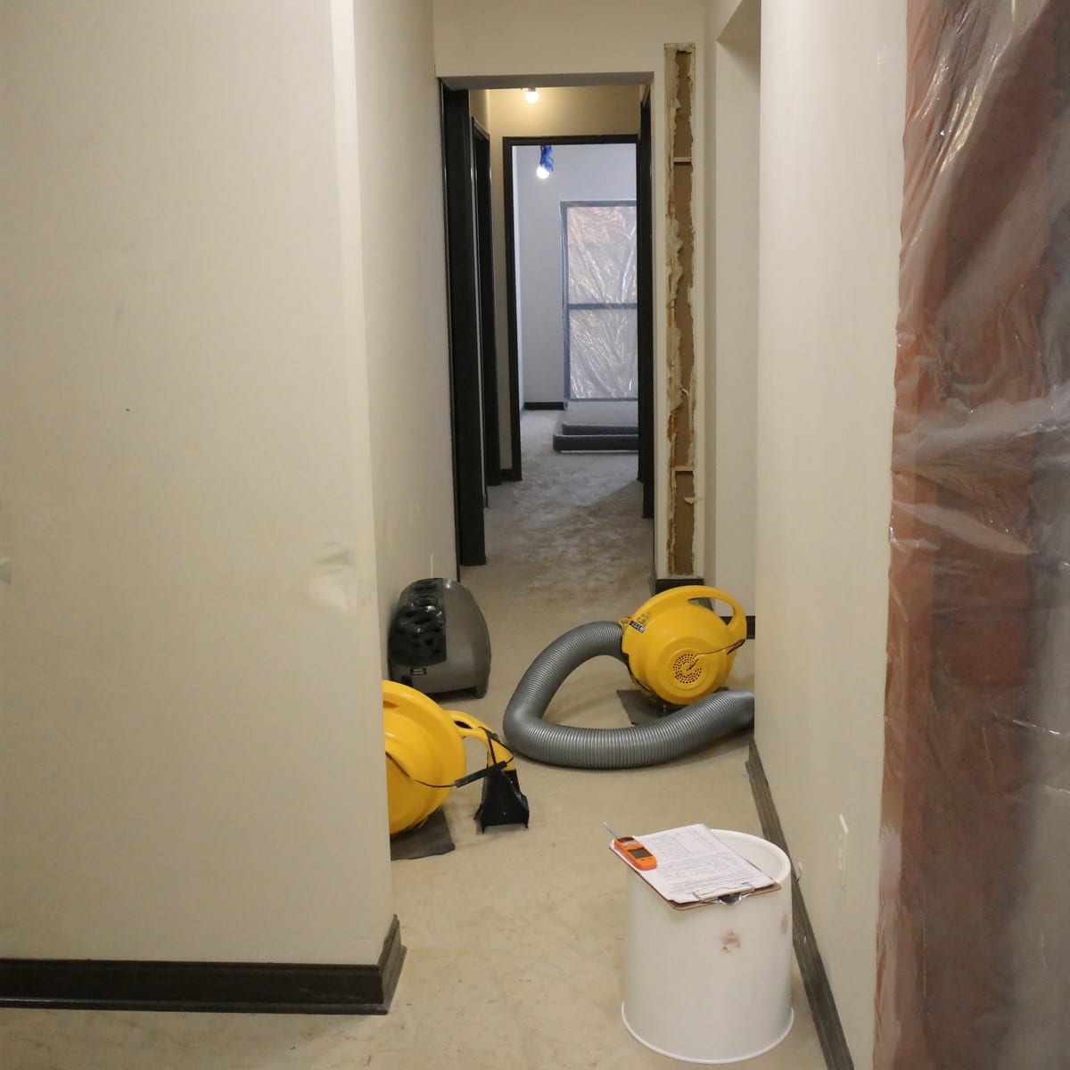 A hallway mid water-damage restoration, air movers and ducting running along the skirting