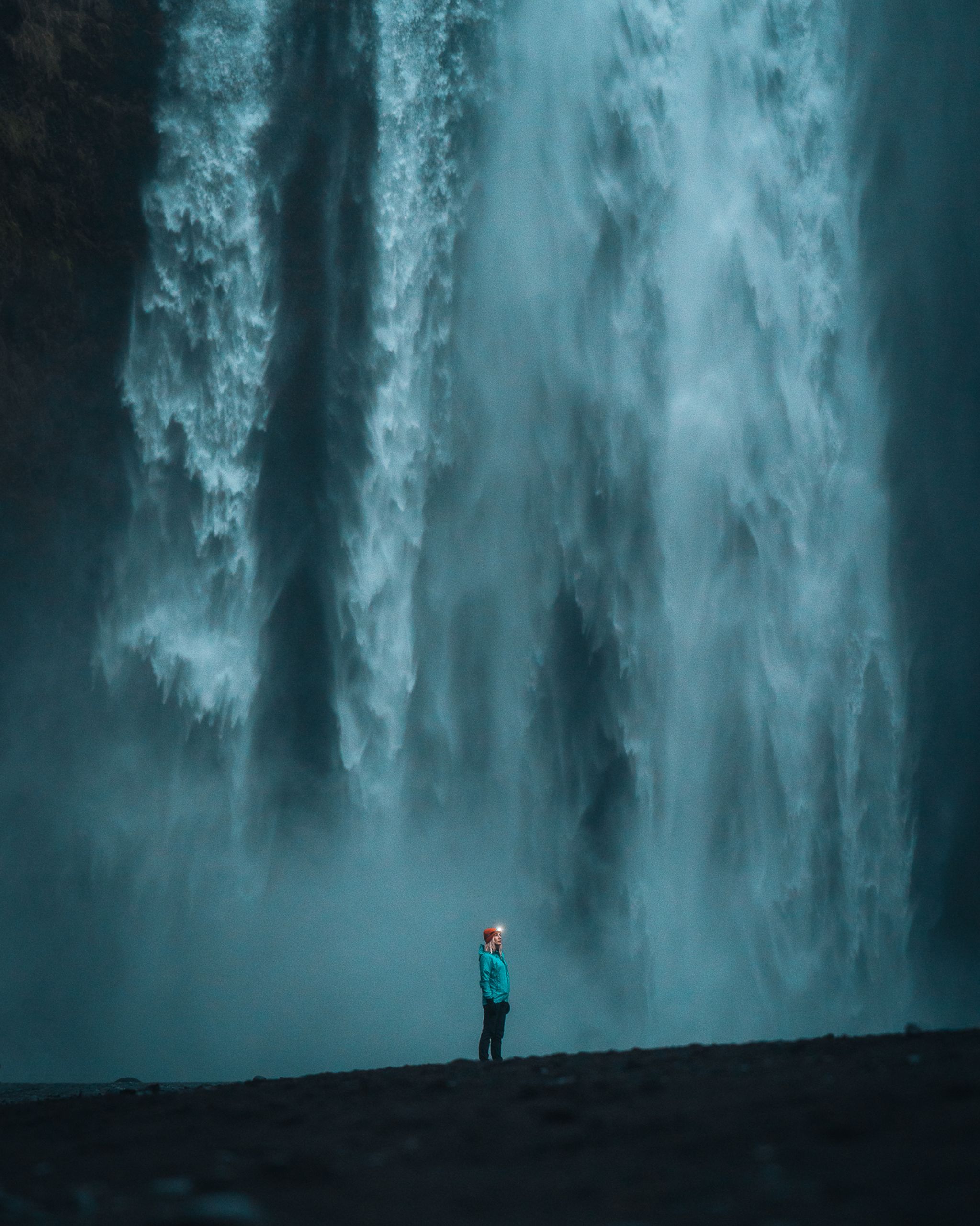 A woman standing next to a huge waterfall in iceland