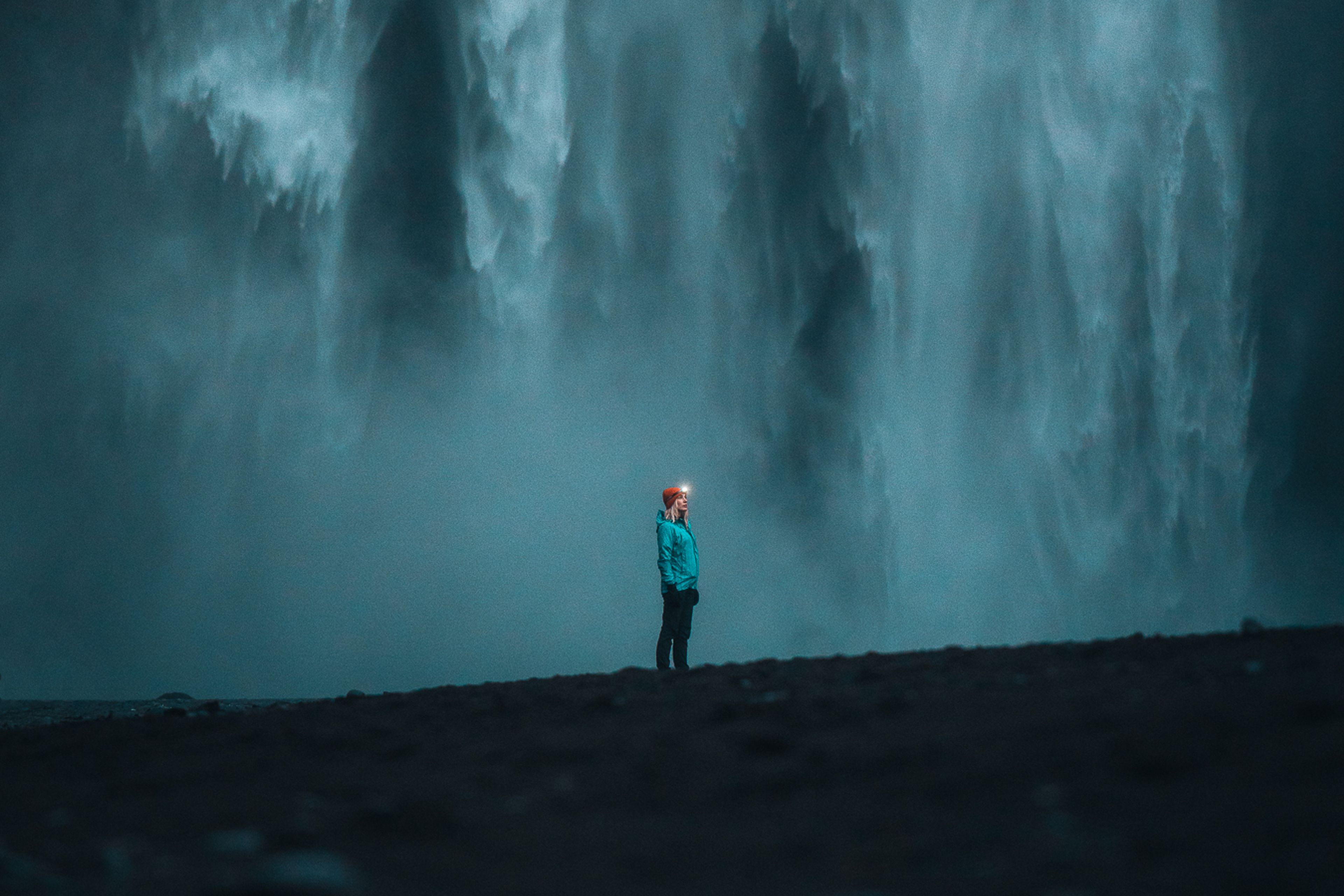A woman standing next to a huge waterfall in iceland