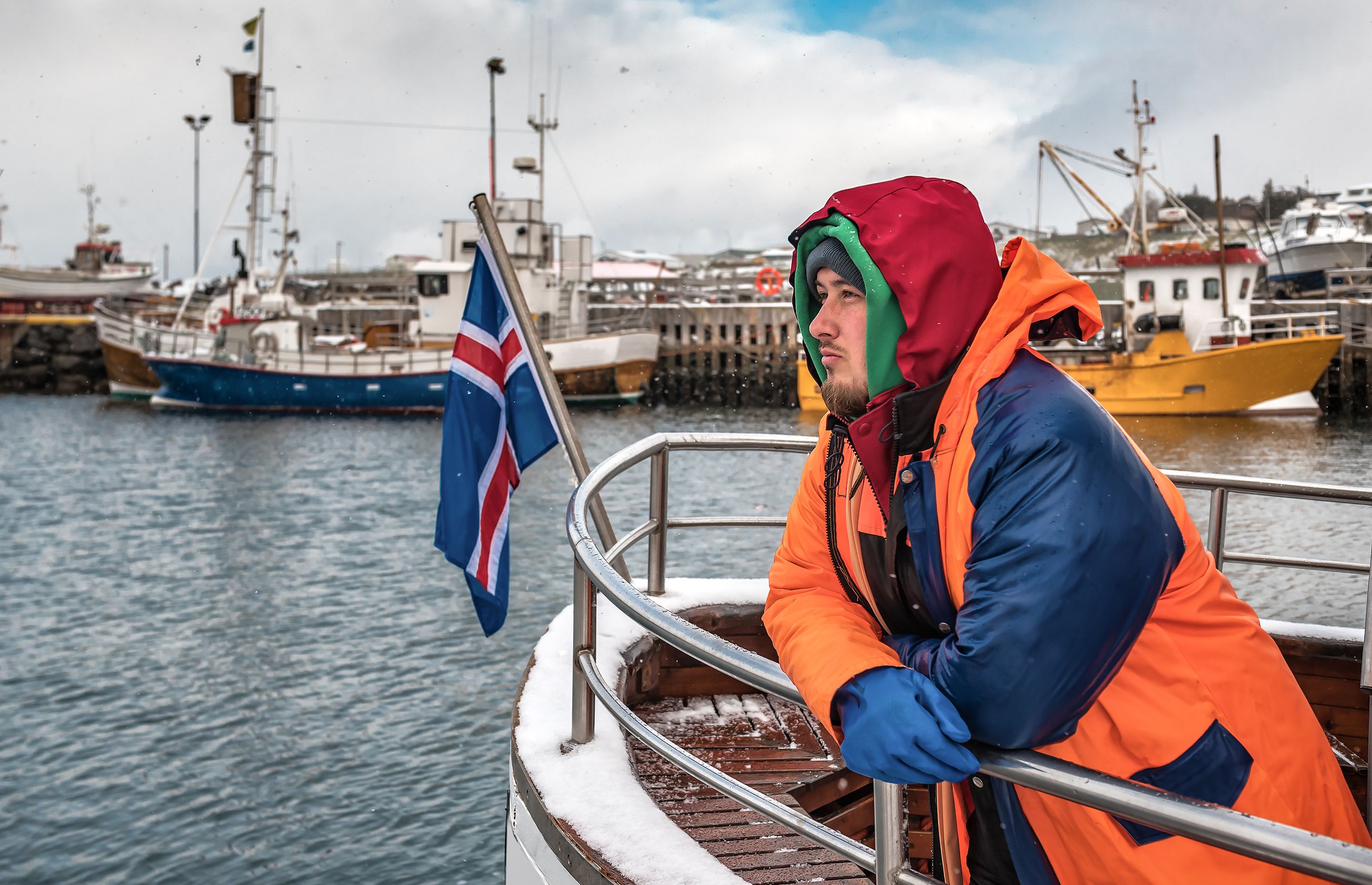 photo of a fisherman particularly well covered, on his Icelandic boat in winter 
