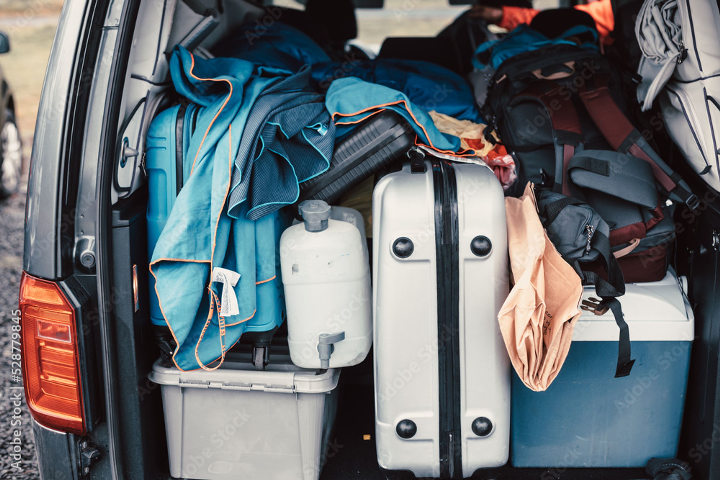 Trunk of car full of suitcases and clothes