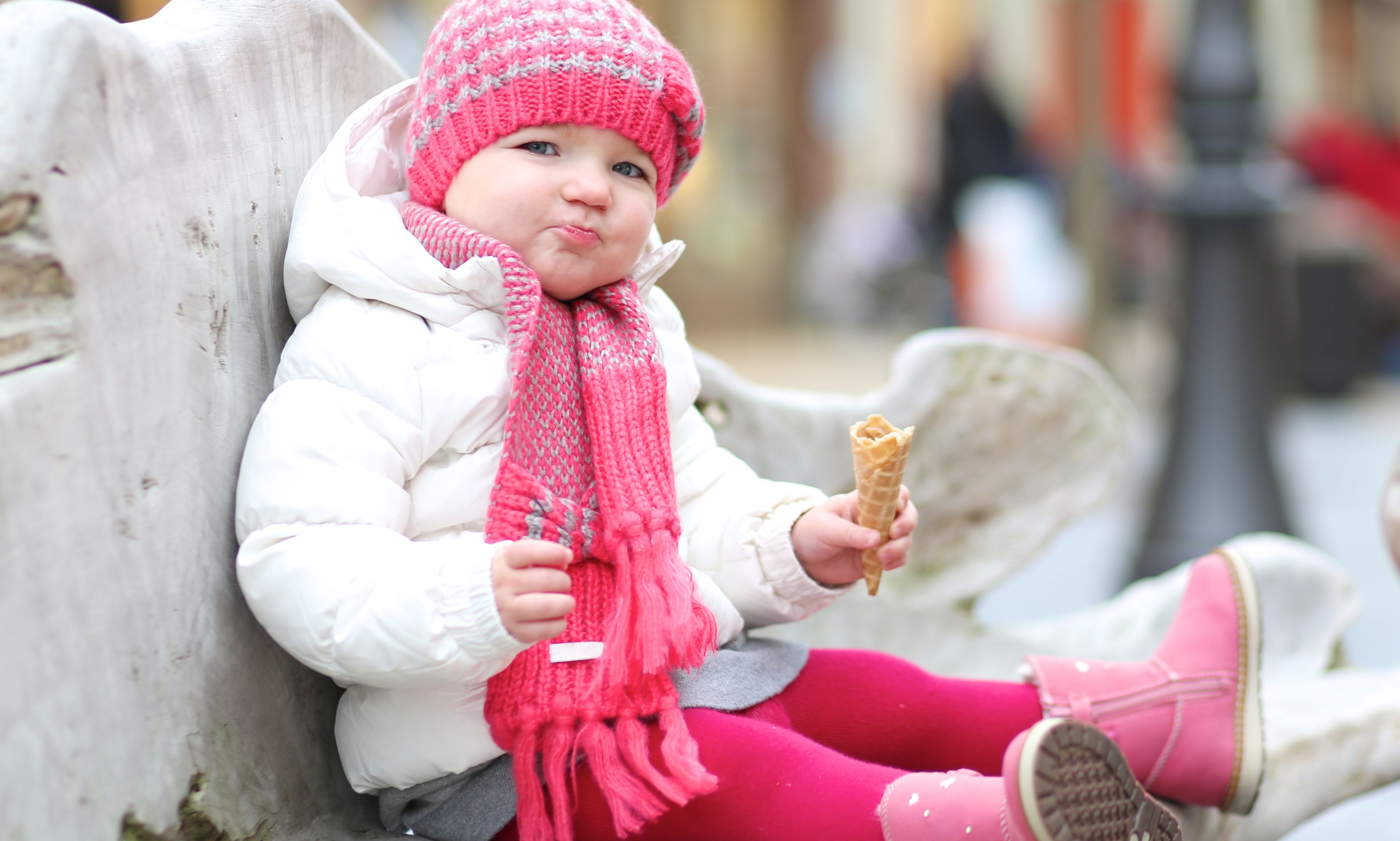 little girl covered in pink to face the Icelandic cold but enjoying the end of her little ice cream on a band  