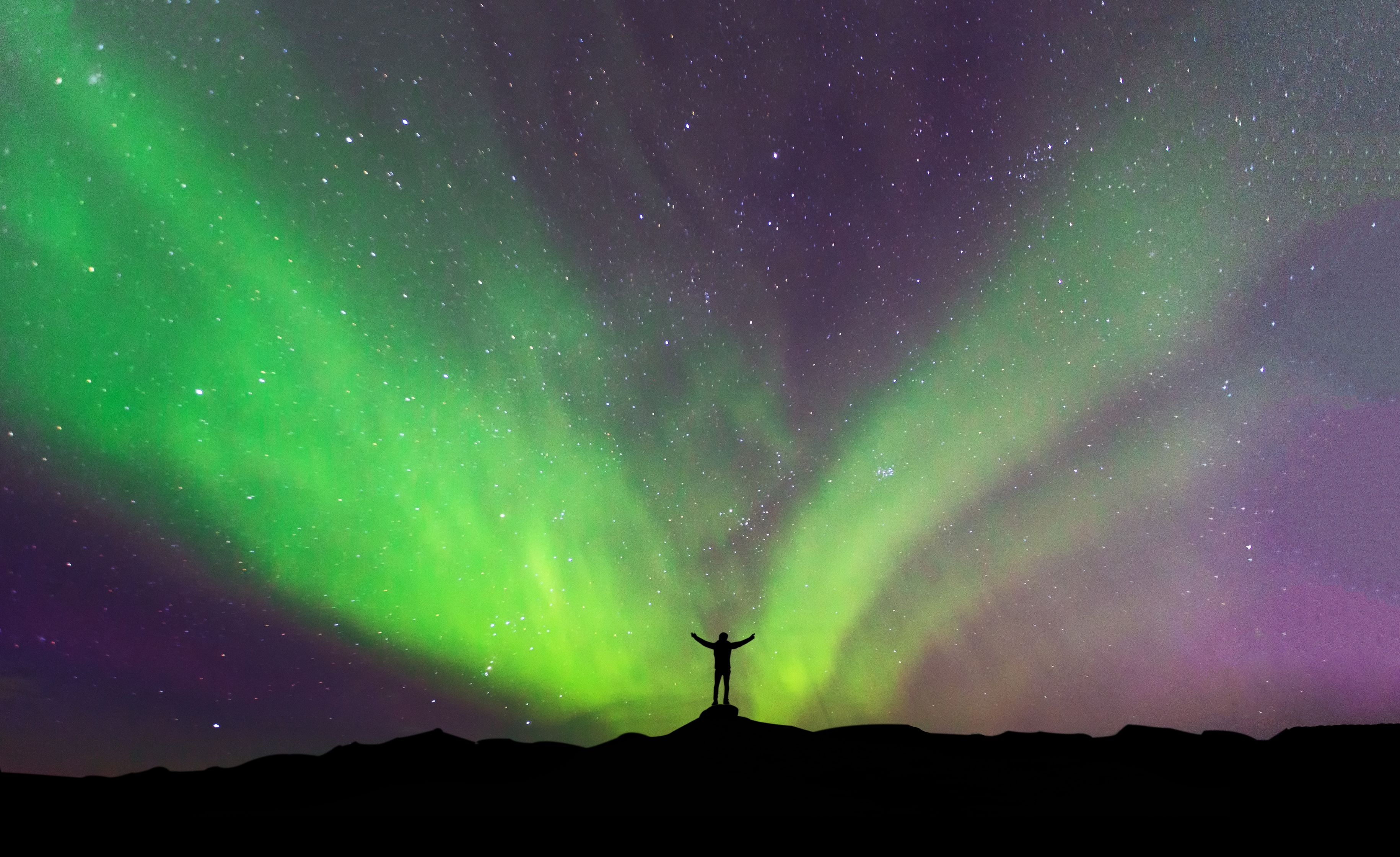 Man standing in front of the Northern Lights in Iceland