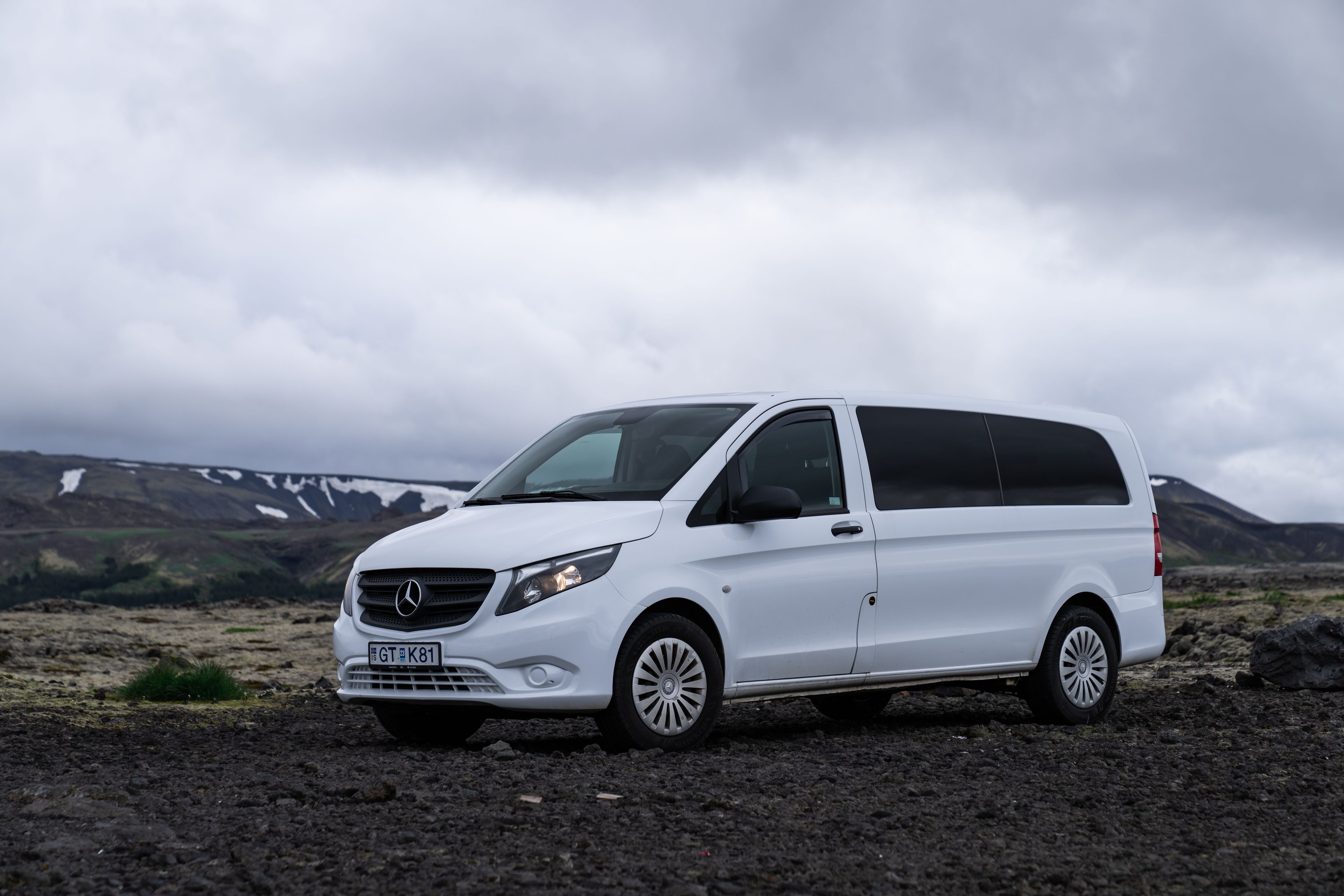 A white Mercedes Benz Vito rental car parked against the stunning landscapes of Iceland.