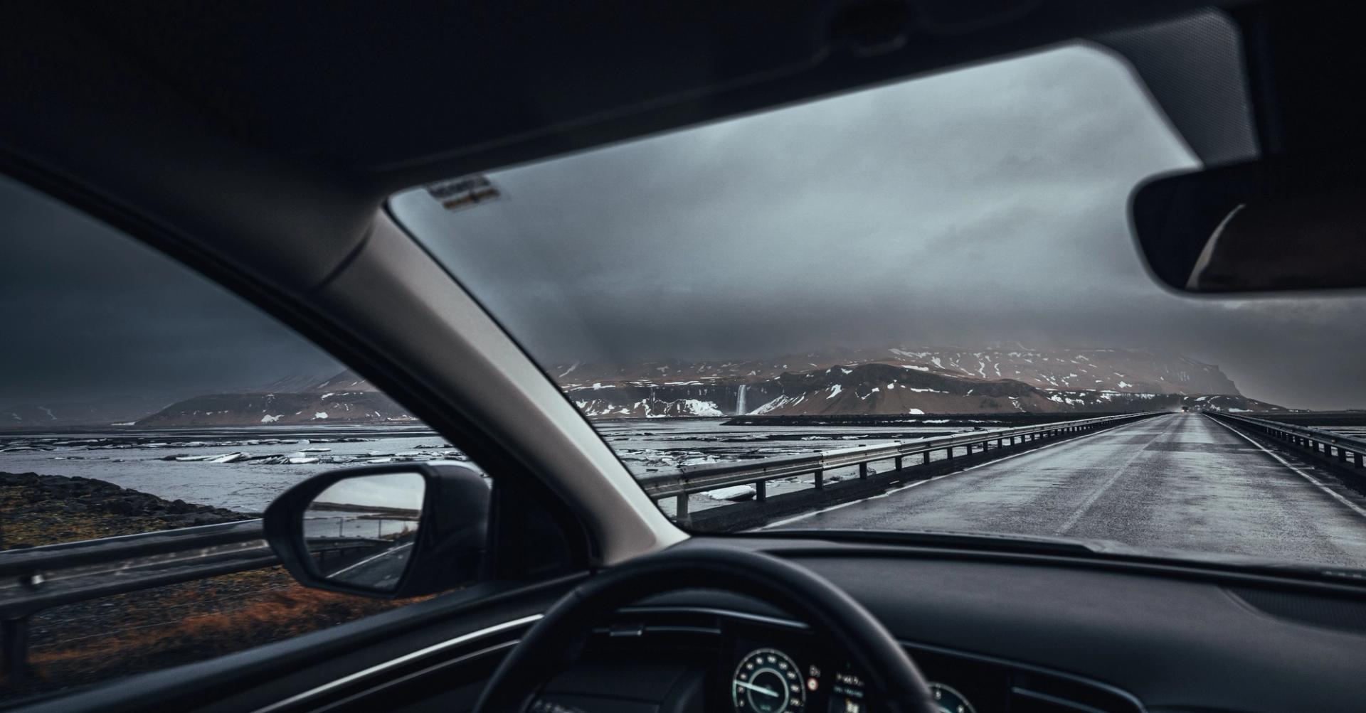 man driving in iceland, the hand on the wheel and the snowy icelandic landscape in the background 