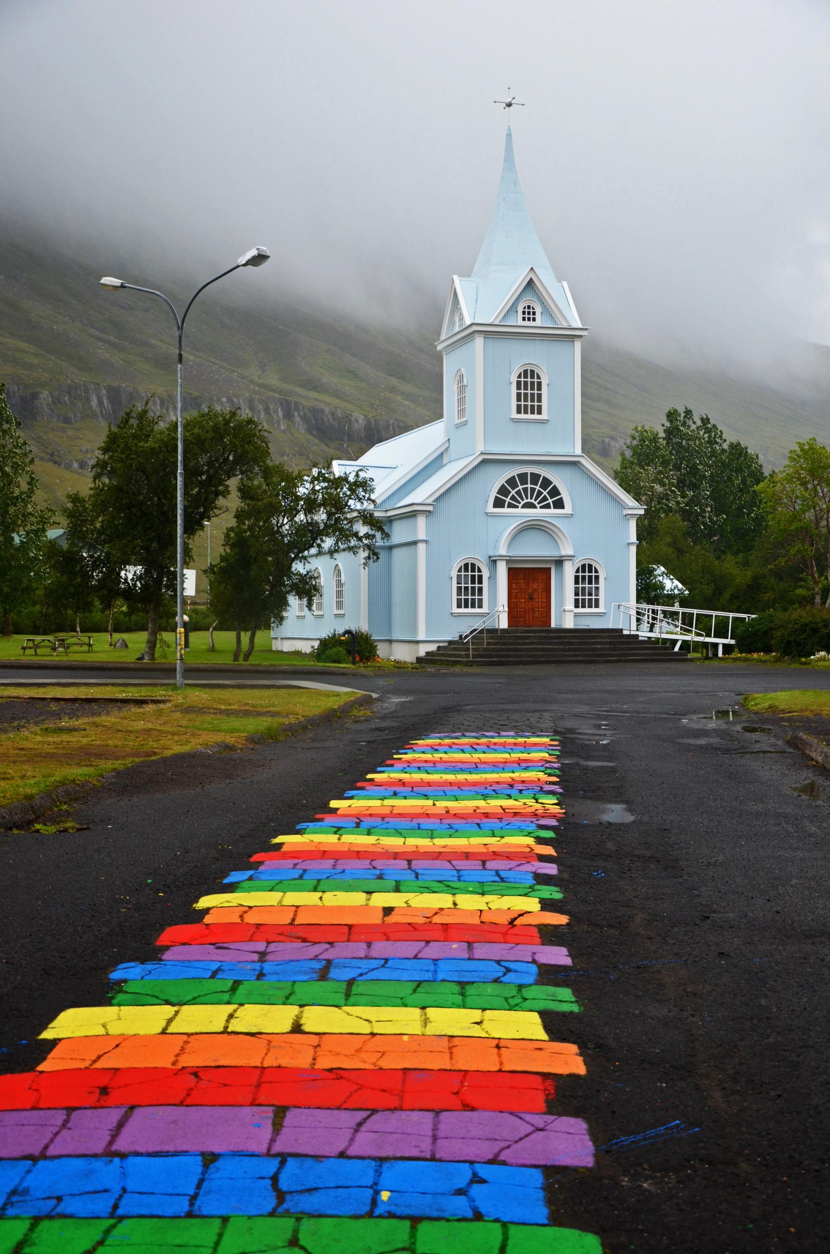 The blue church of Seyðisfjörður with rainbow road leading to it in east of Iceland