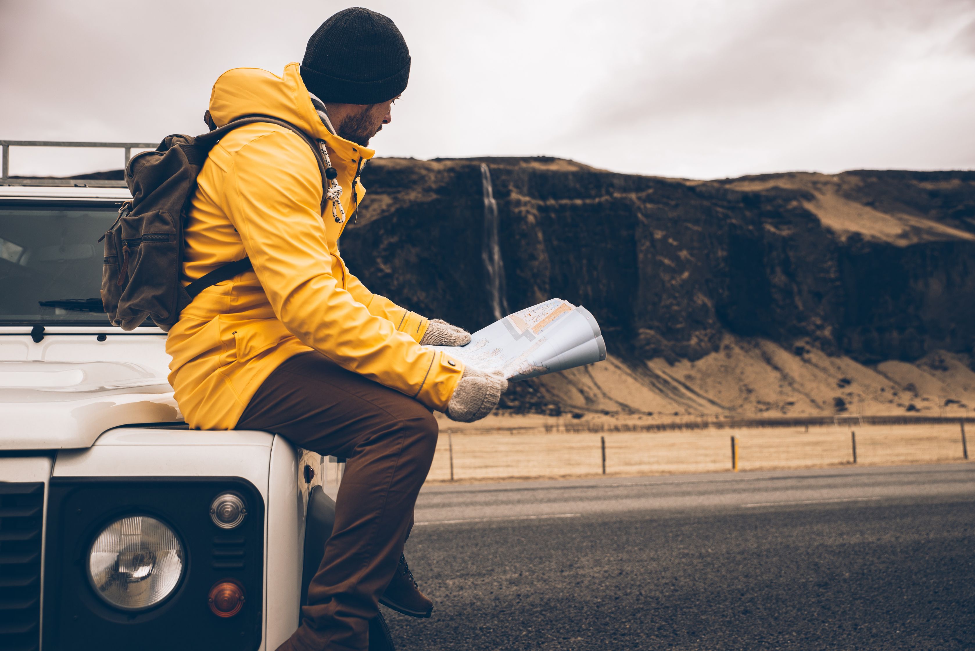 Man sitting on his 4x4 checking a map of Iceland