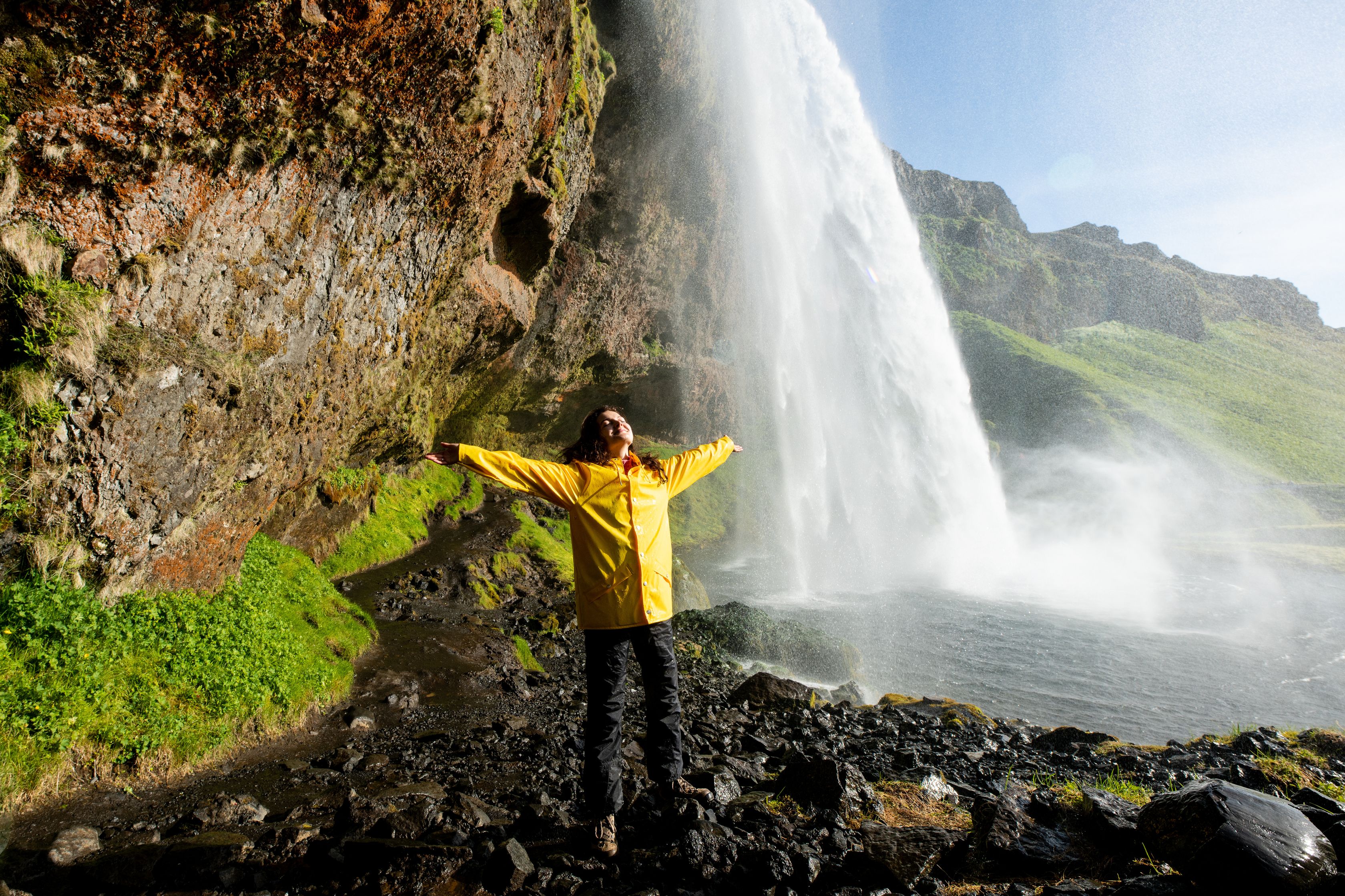 Happy tourist under Seljalandfoss waterfall, Iceland