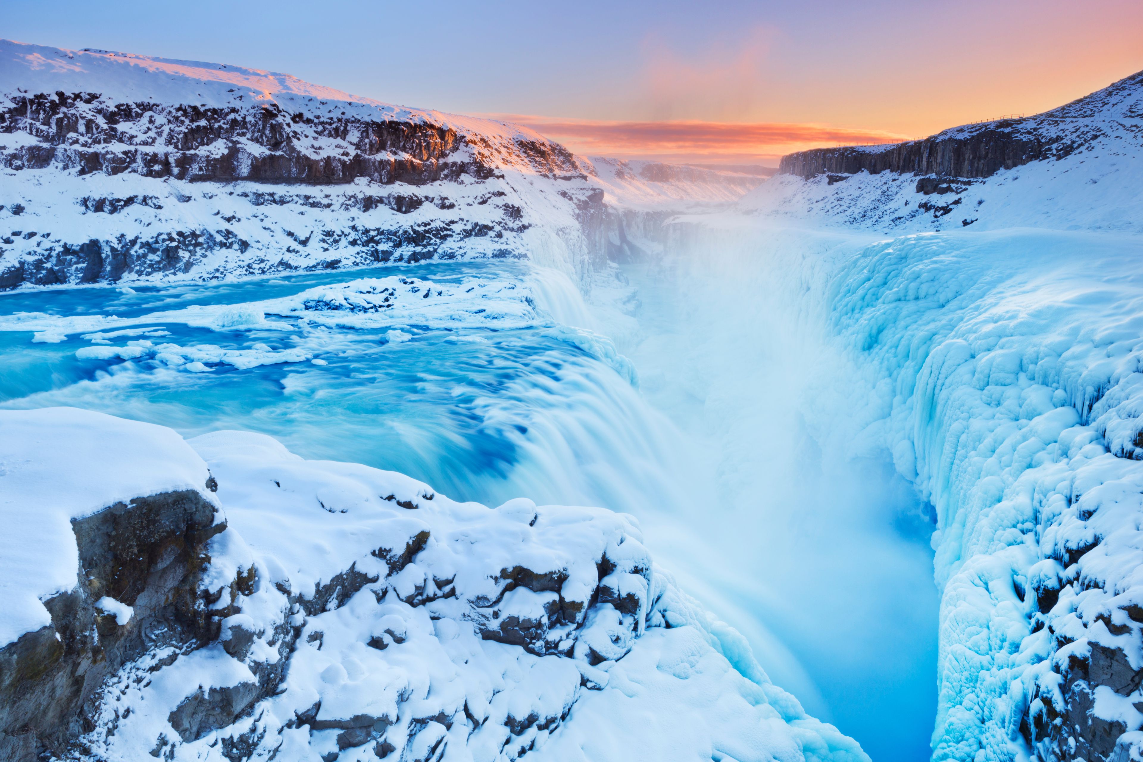sun rises from Frozen Gullfoss Waterfall in winter on the golden circle route