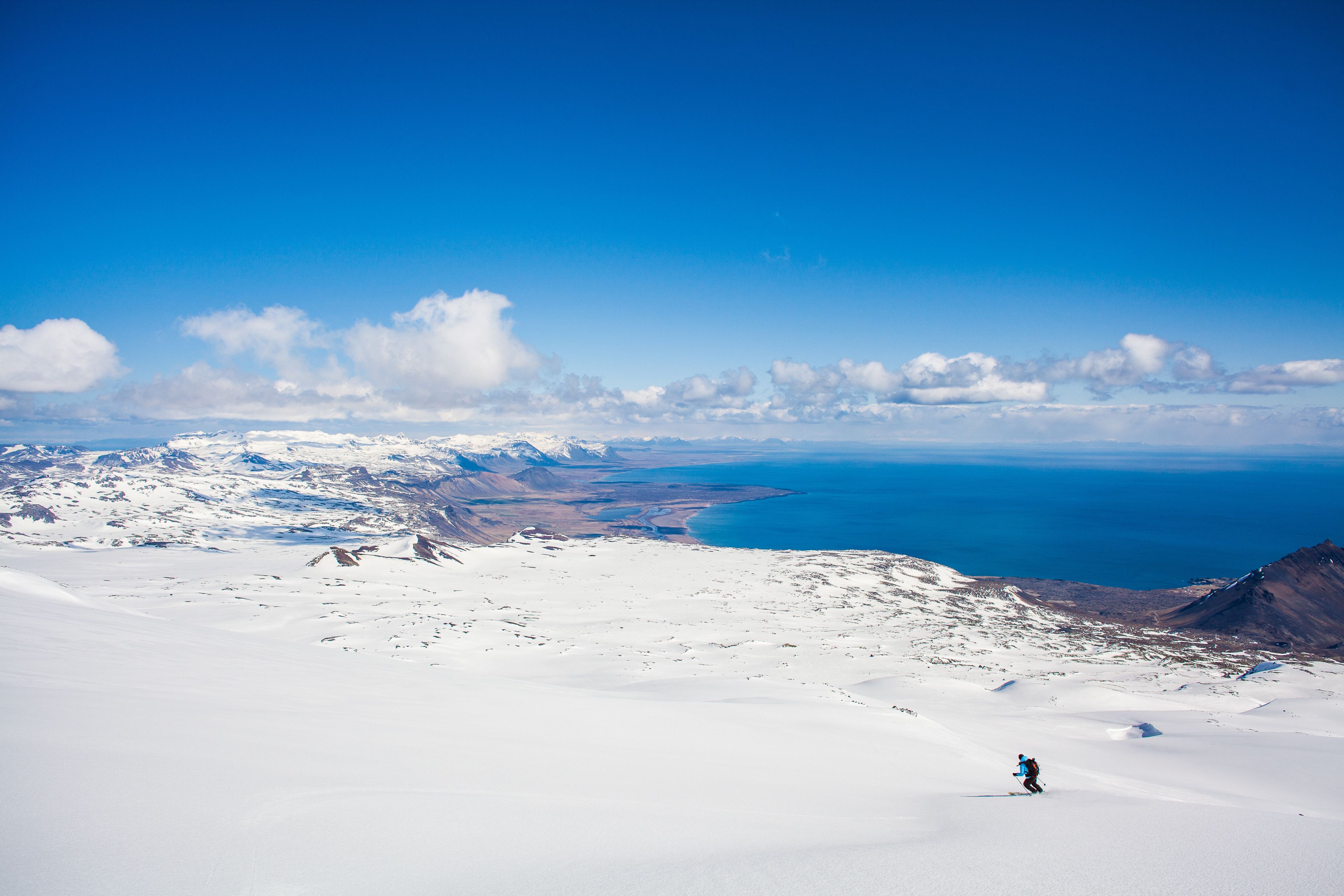 Skiier skiing a mountian down with the sea in the backgroun, Iceland