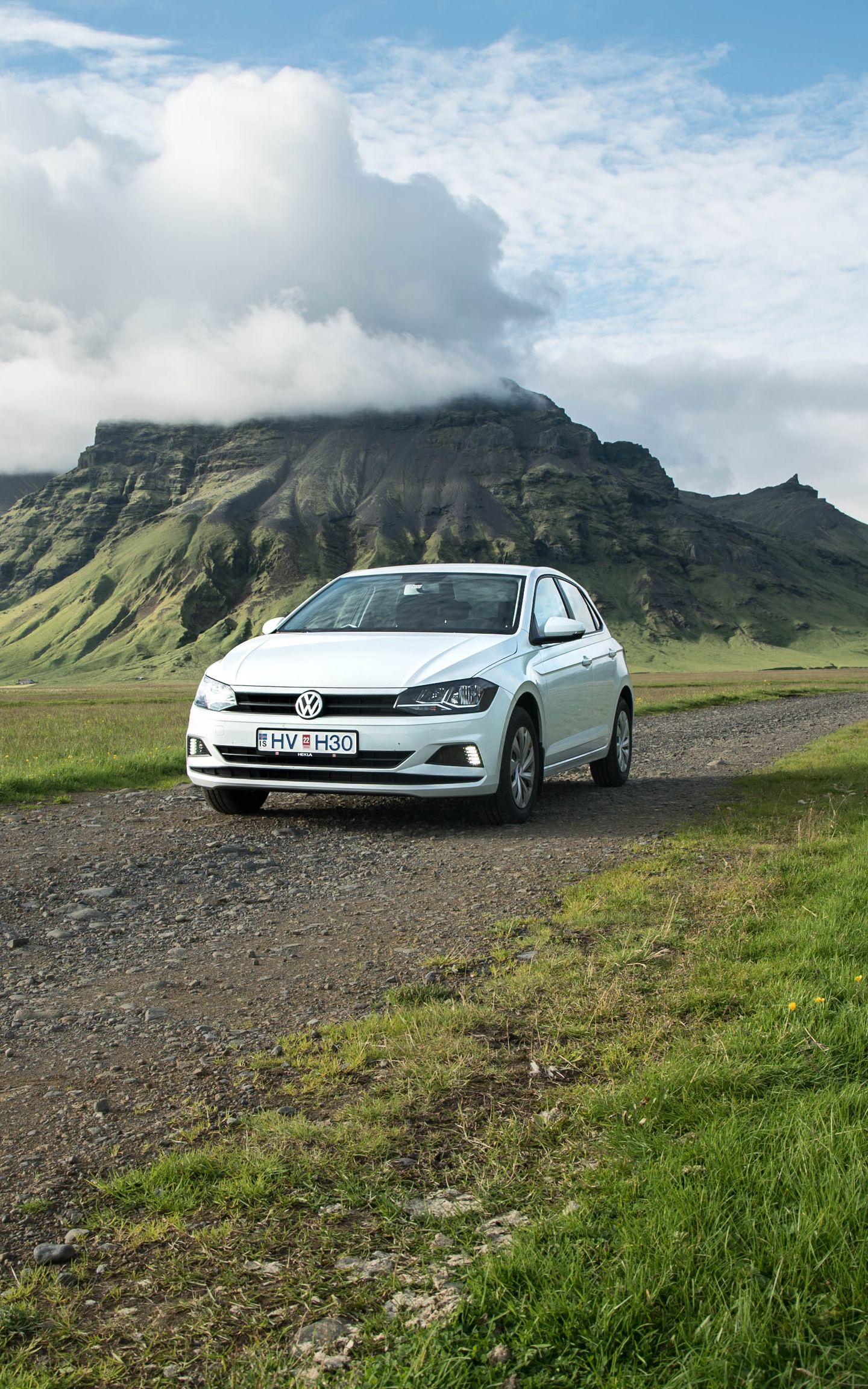 A small economy rental car traversing the beautiful Icelandic landscapes.