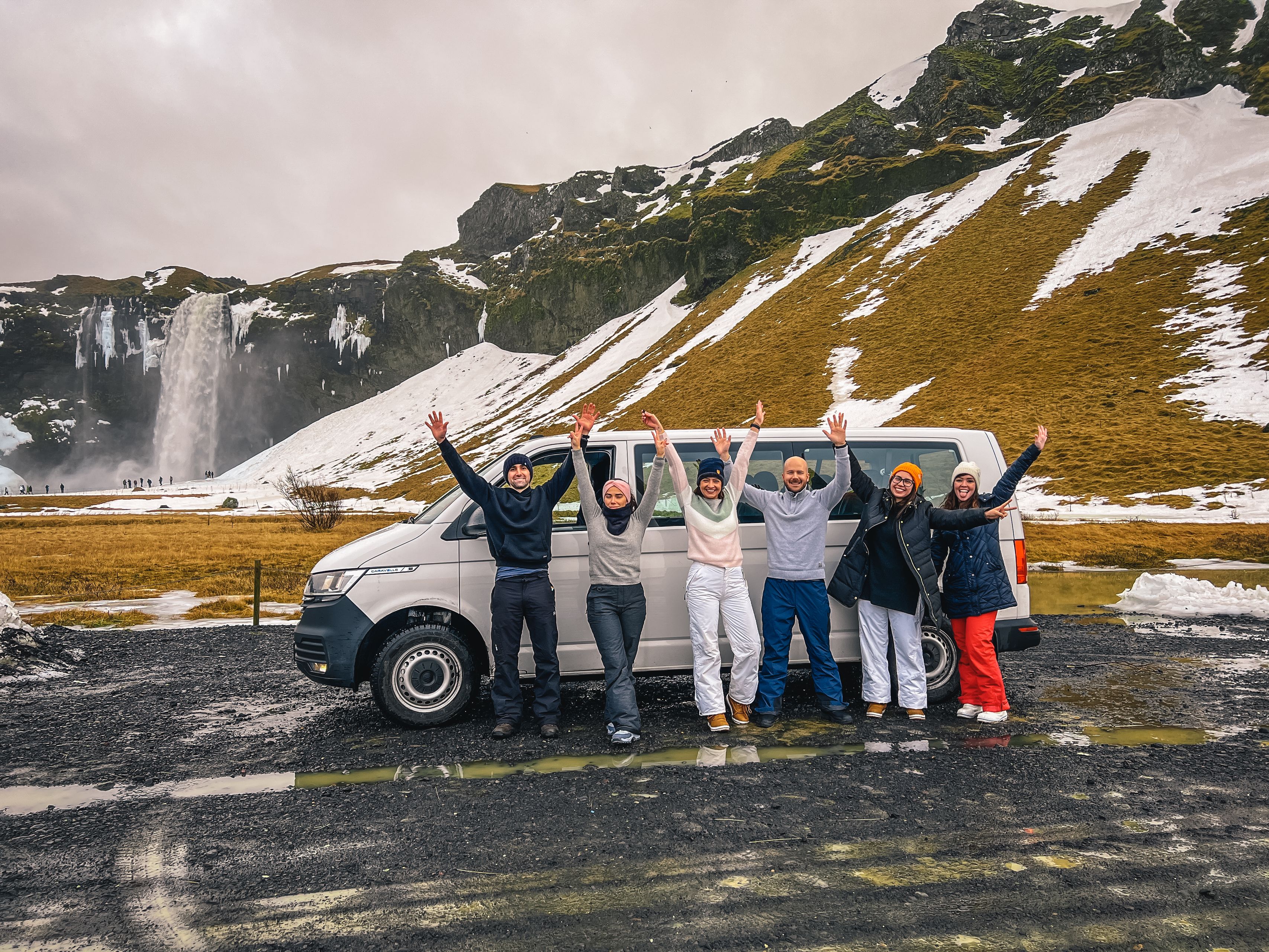 Group of happy people near a 9 seater rental car van in iceland