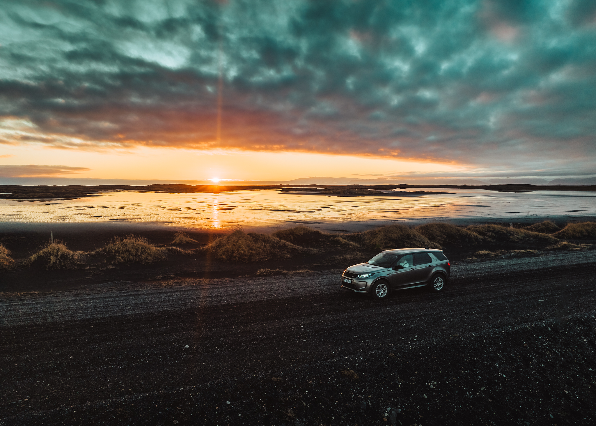 Land Rover Discovery Sport auf der Straße geparkt, während die Sonne untergeht
