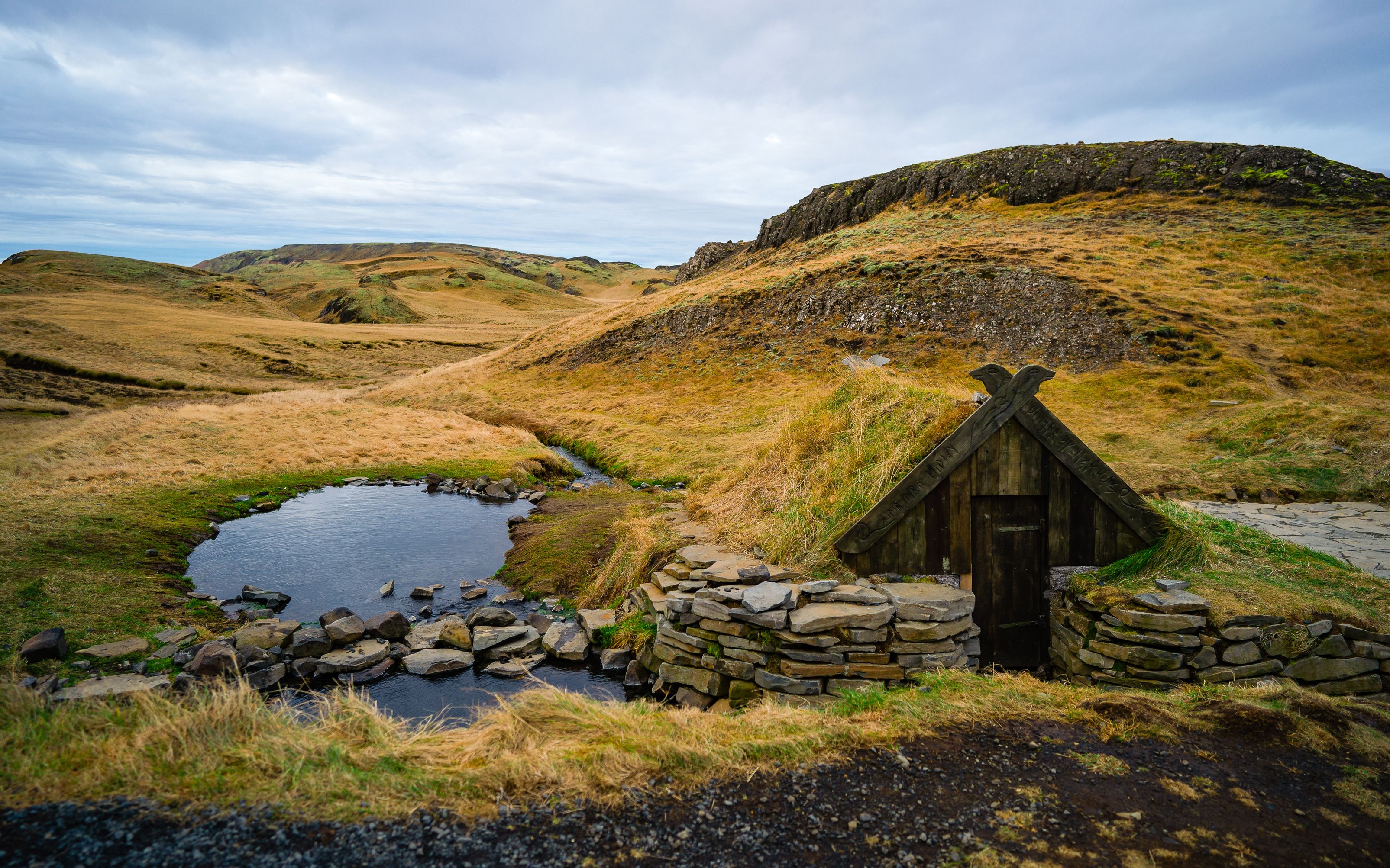 A small hot spring in Iceland with a small turf house next to it. The Hrunalaug Hot Spring.