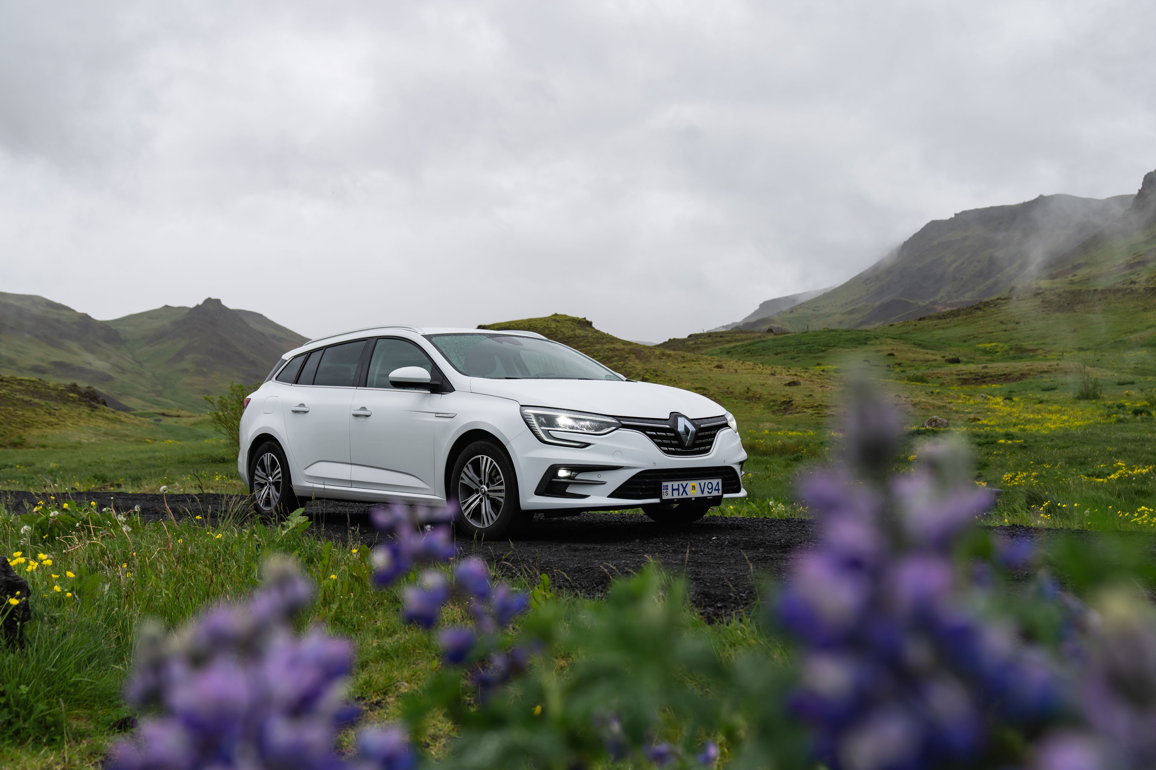 A white Renault Megane wagon rental car parked amidst the stunning landscapes of Iceland.