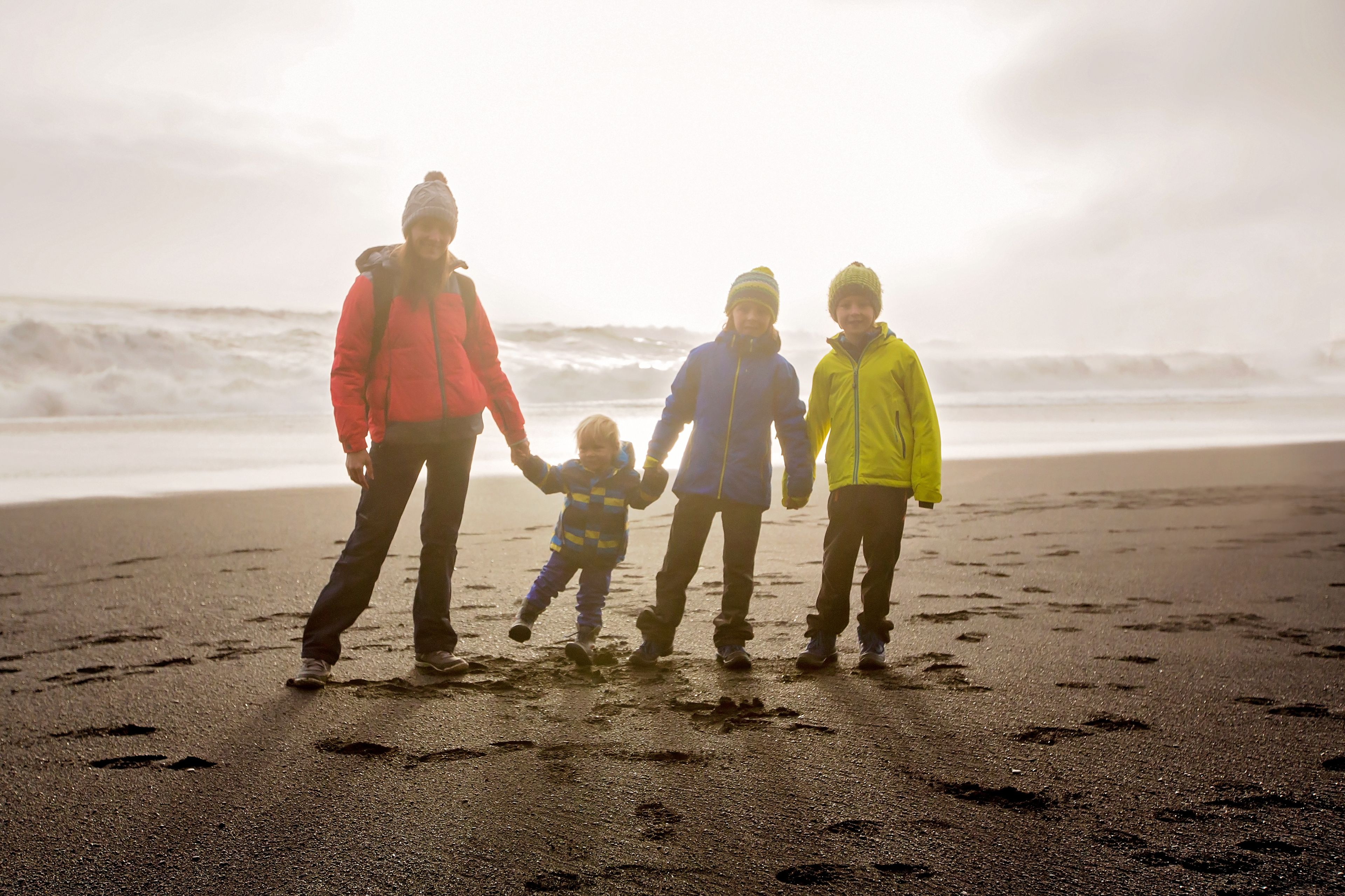 Madre y sus tres hijos en la playa de arena negra Reynisfjara, Islandia