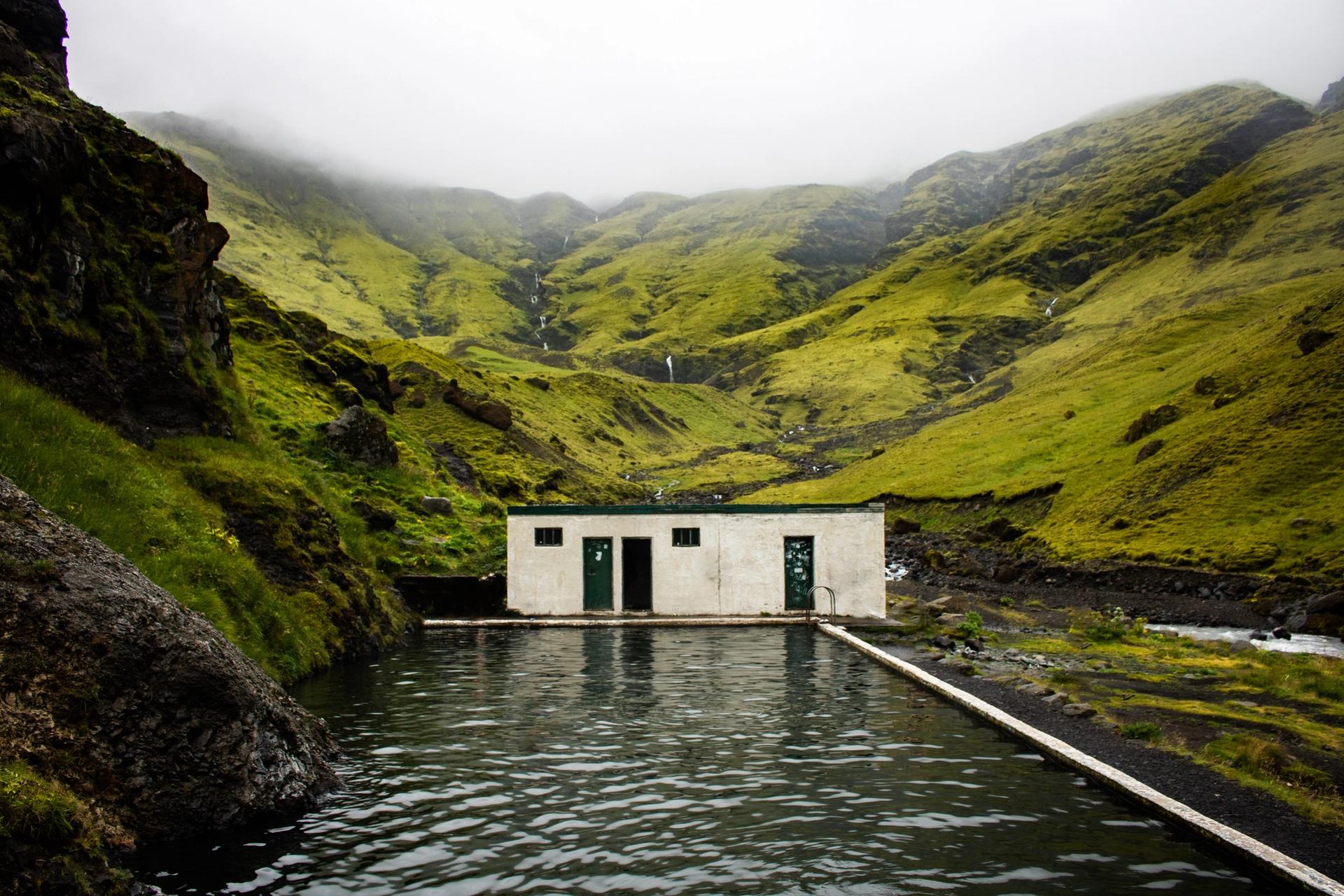 Seljavallalaug Hot Spring in Iceland in the middle of nowhere surrounded by green grass and mountains