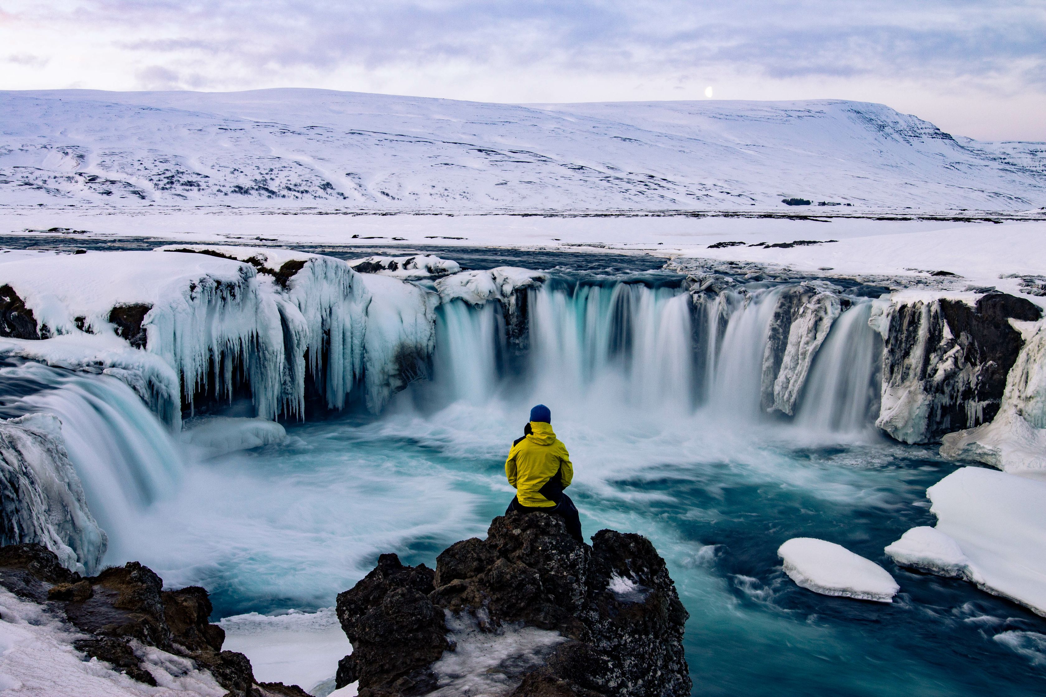 Man sitting on a rock in front of Godafoss during winter