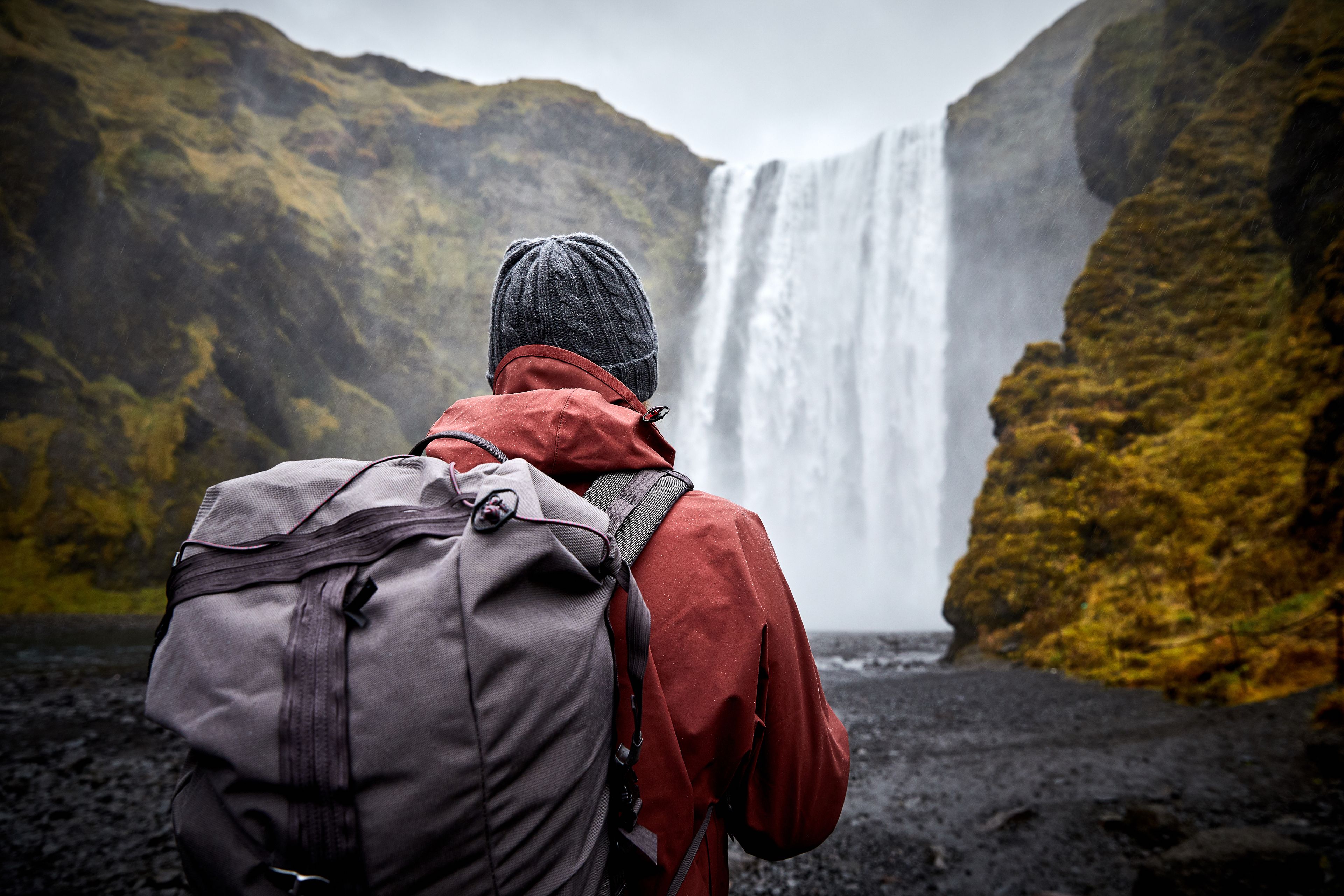 Hiker backpacker looking at Skogafoss Waterfall Southern Iceland during Spring