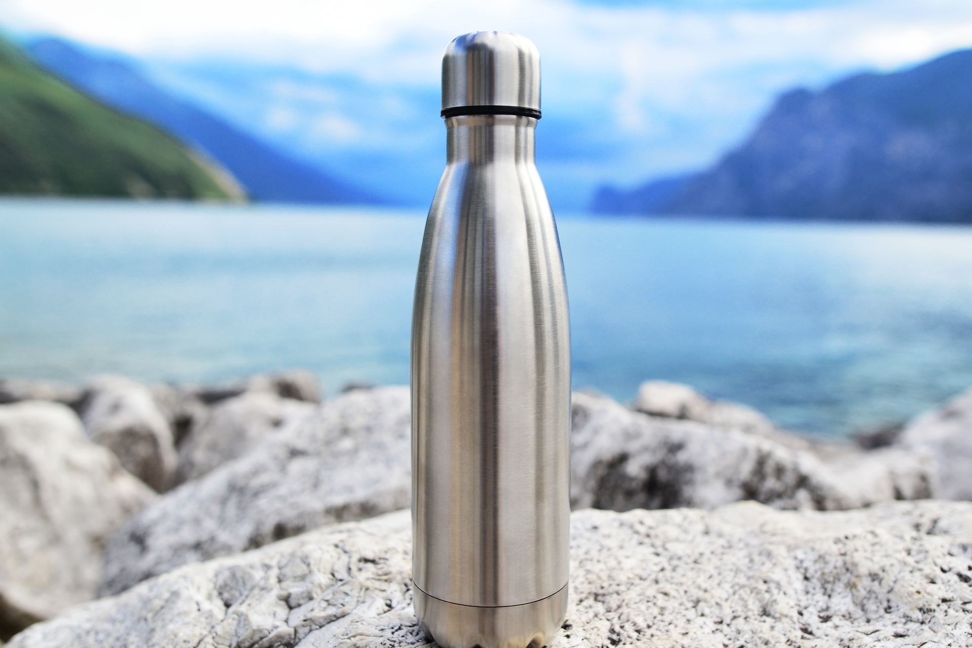 Close-up of a steel thermosensitive water bottle on a lake background in the middle of the Icelandic mountains. Zero waste. 