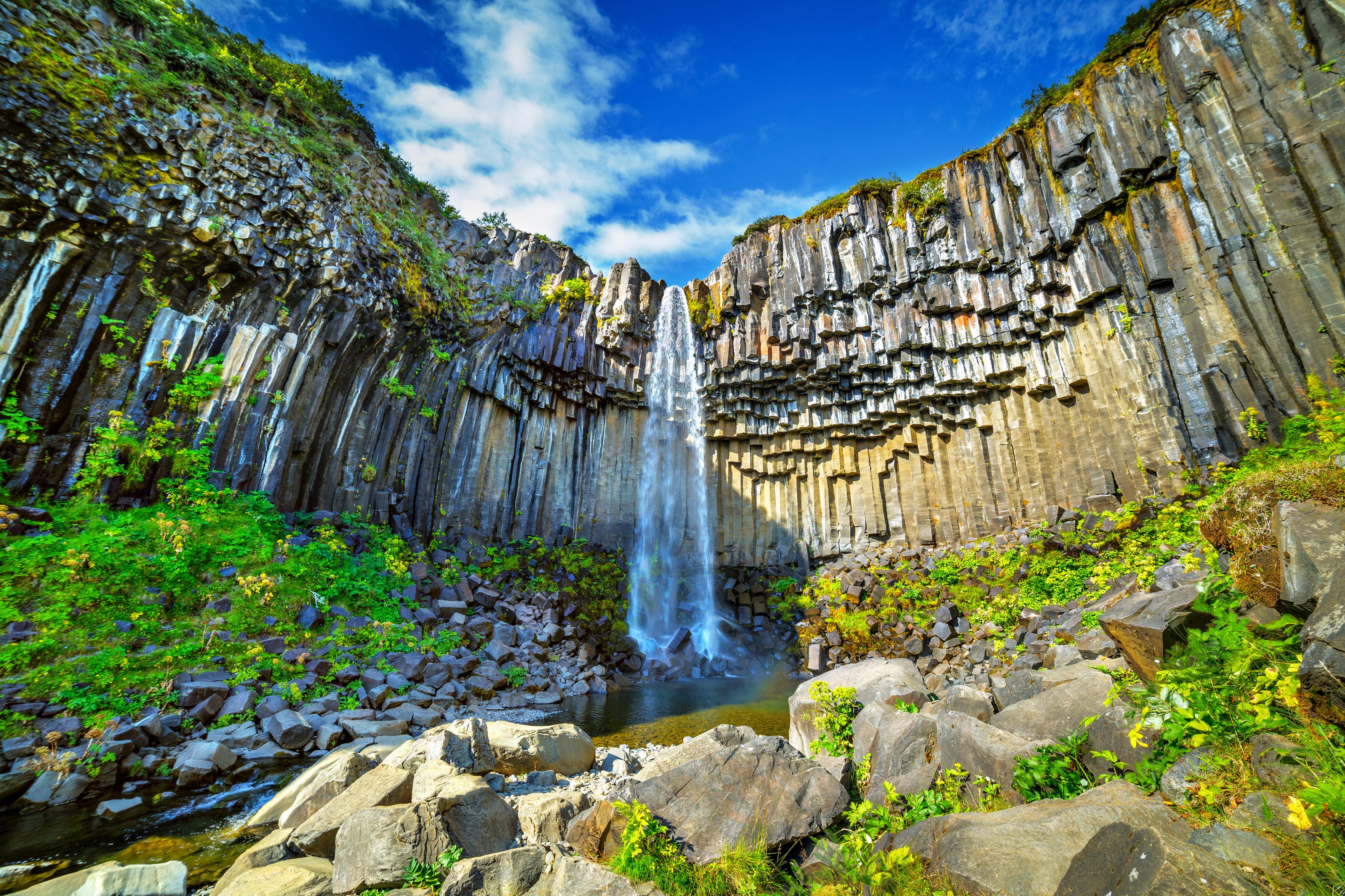 A stunning view of Svartifoss Waterfall in Iceland illuminated by bright sunlight.