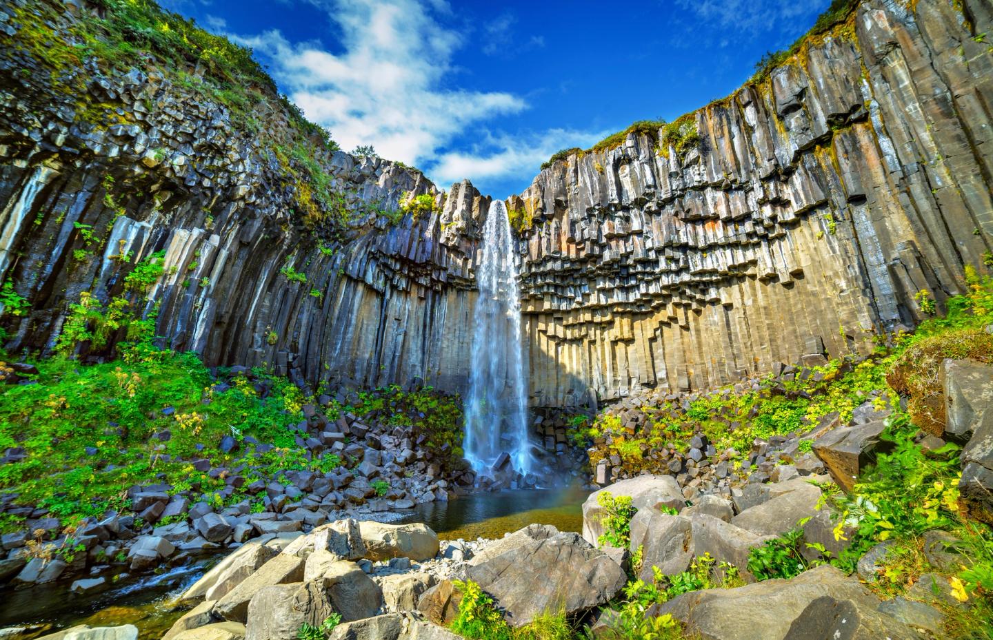 A stunning view of Svartifoss Waterfall in Iceland illuminated by bright sunlight.