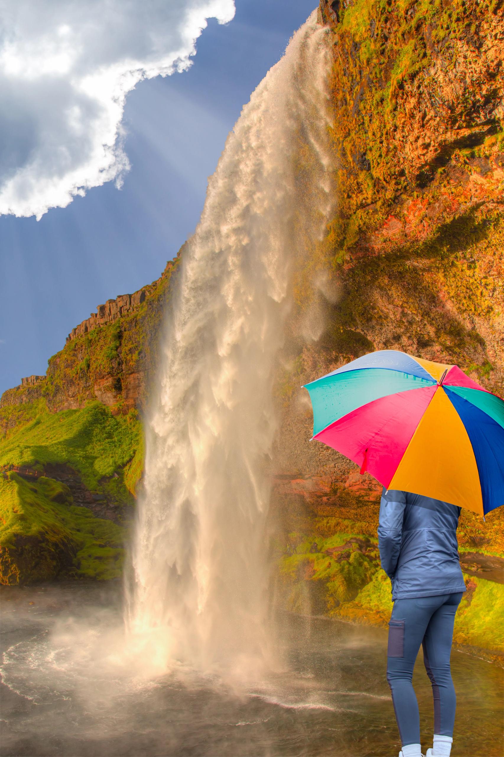 Girl with umbrella in front of Iceland Waterfall