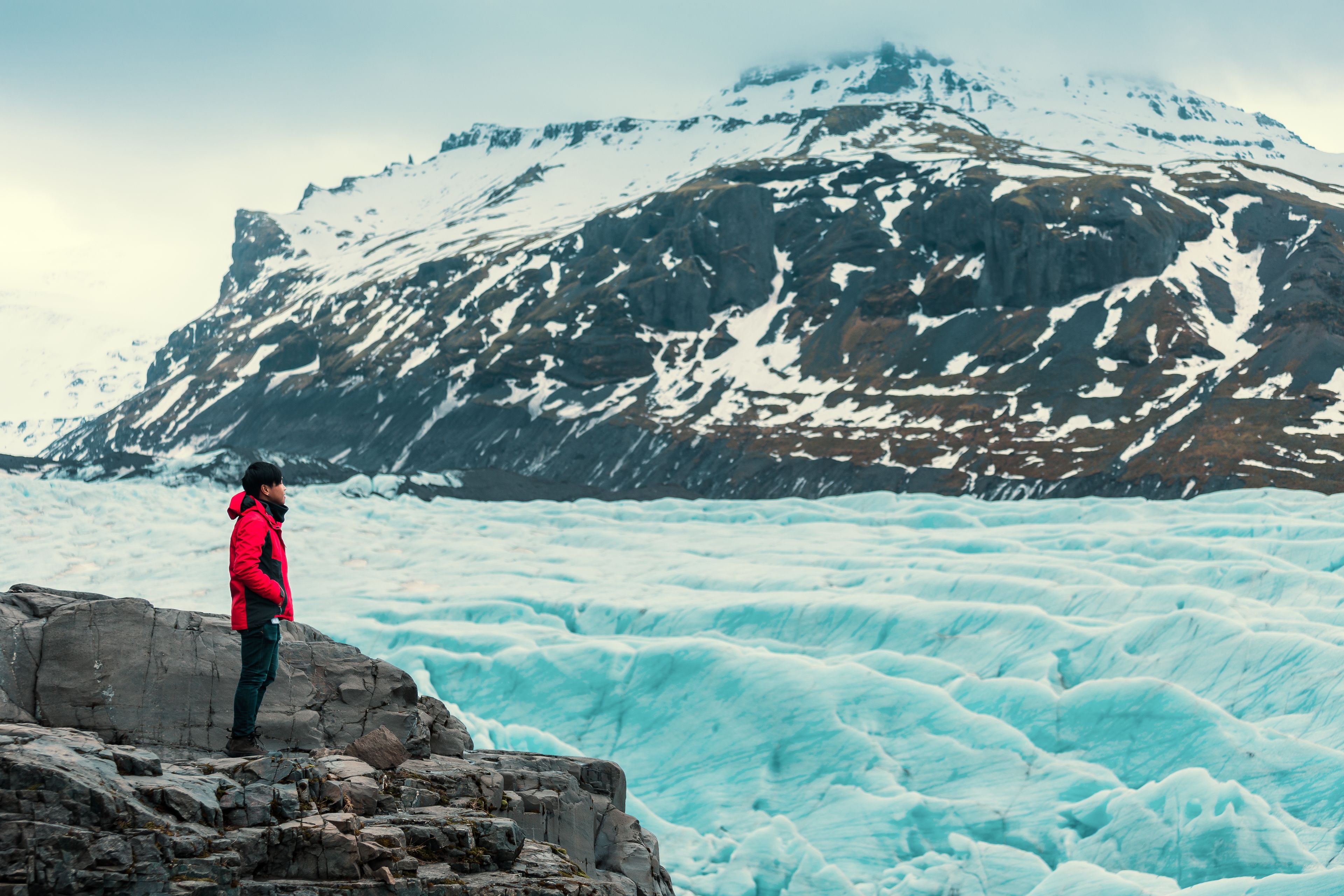 Man in red jacket looking the glacier in iceland