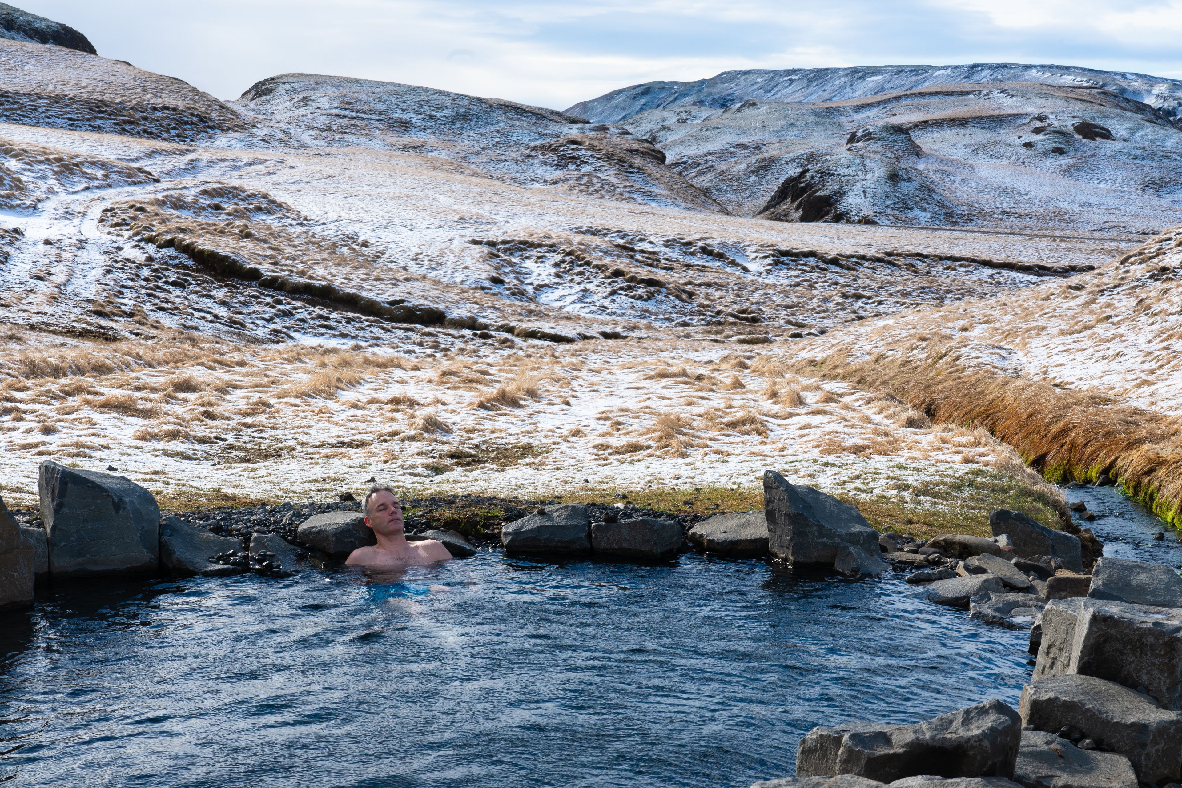 Man enjoying hot springs in a natural pool in Iceland in winter