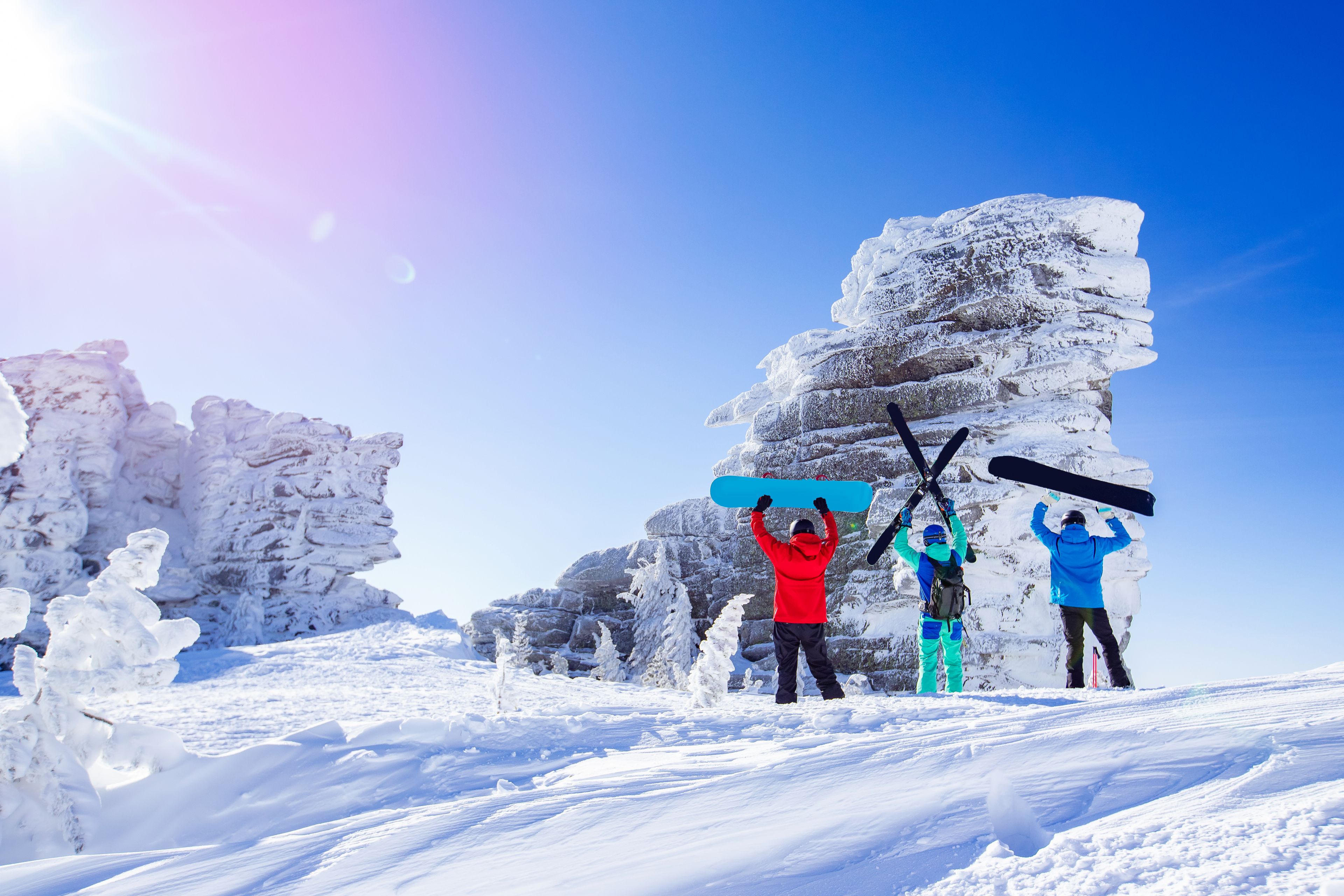 Three snowboarders and skiers in the mountain