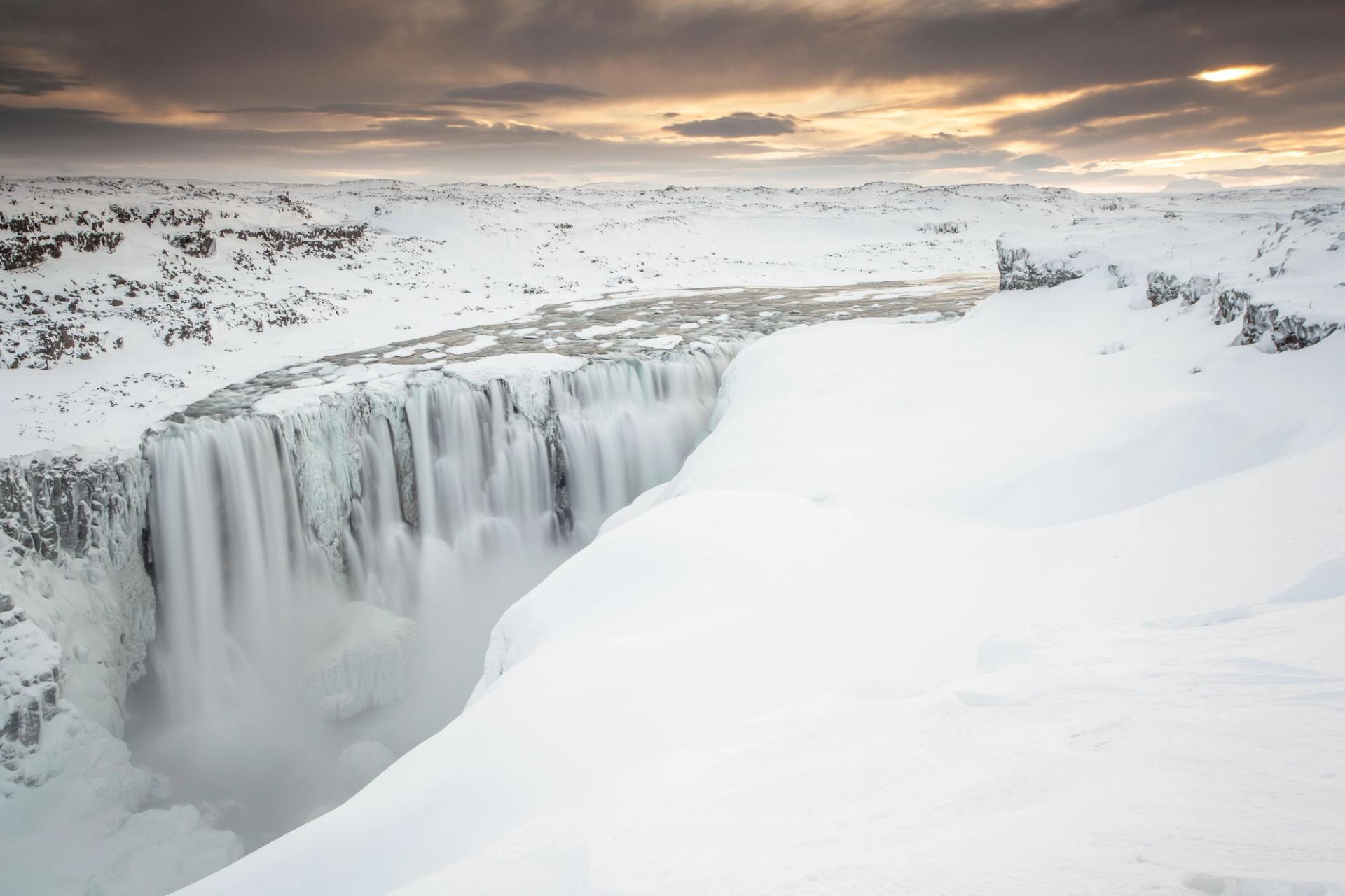 Dettifoss waterfall in Iceland during winter, surrounded by snow and ice.