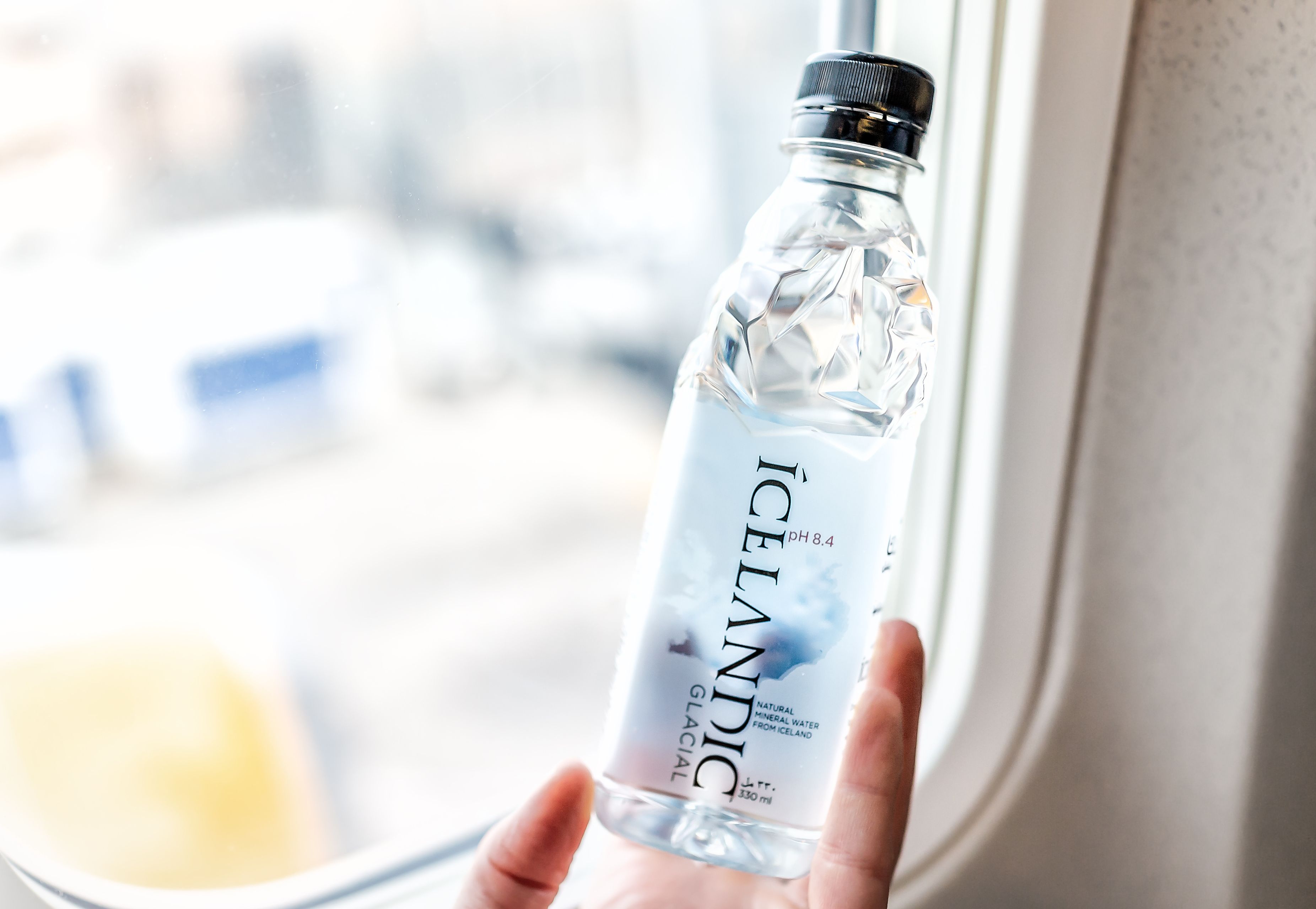 man returning from his trip to Iceland with a bottle of Icelandic Glacial water, particularly pure water 