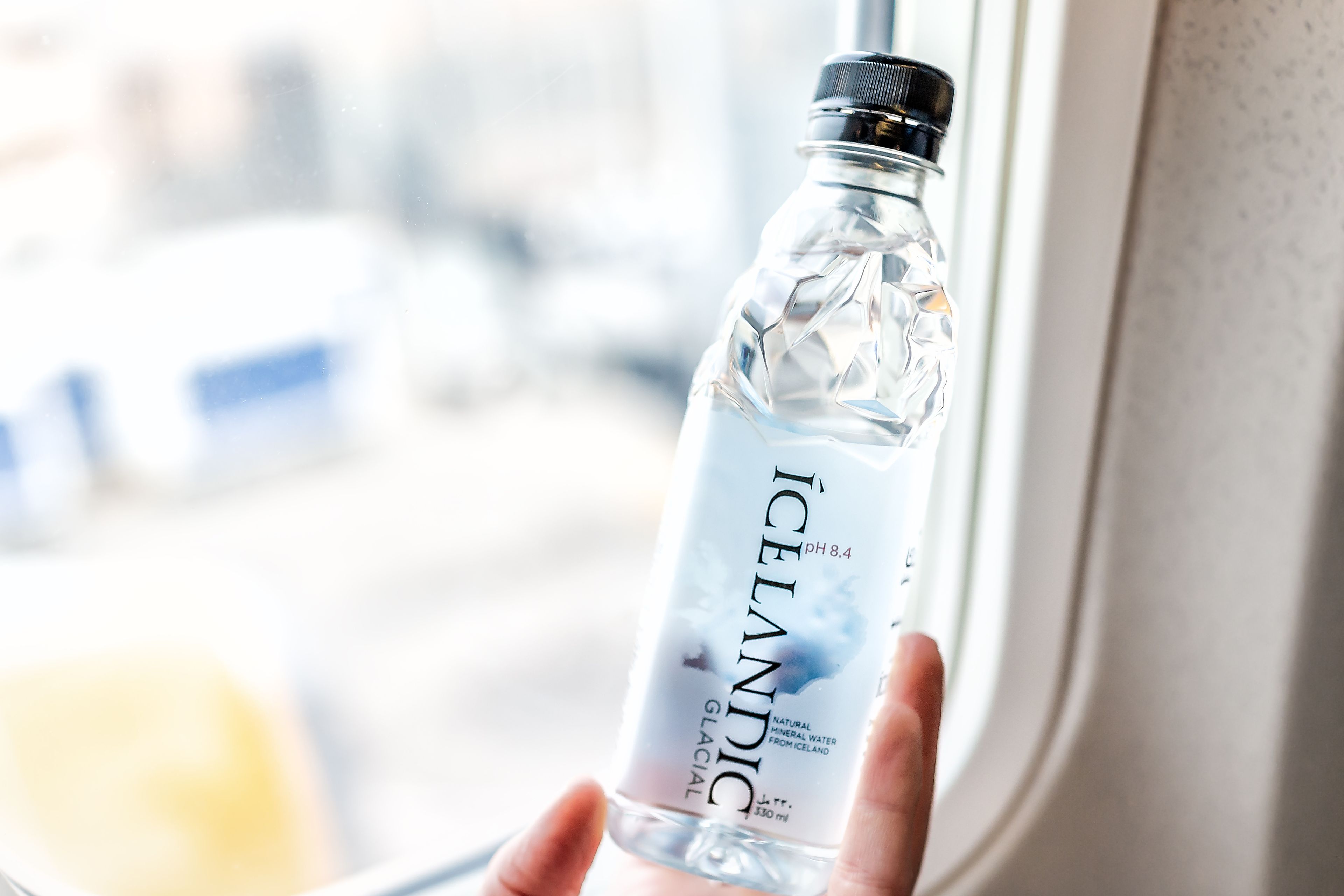 man returning from his trip to Iceland with a bottle of Icelandic Glacial water, particularly pure water 