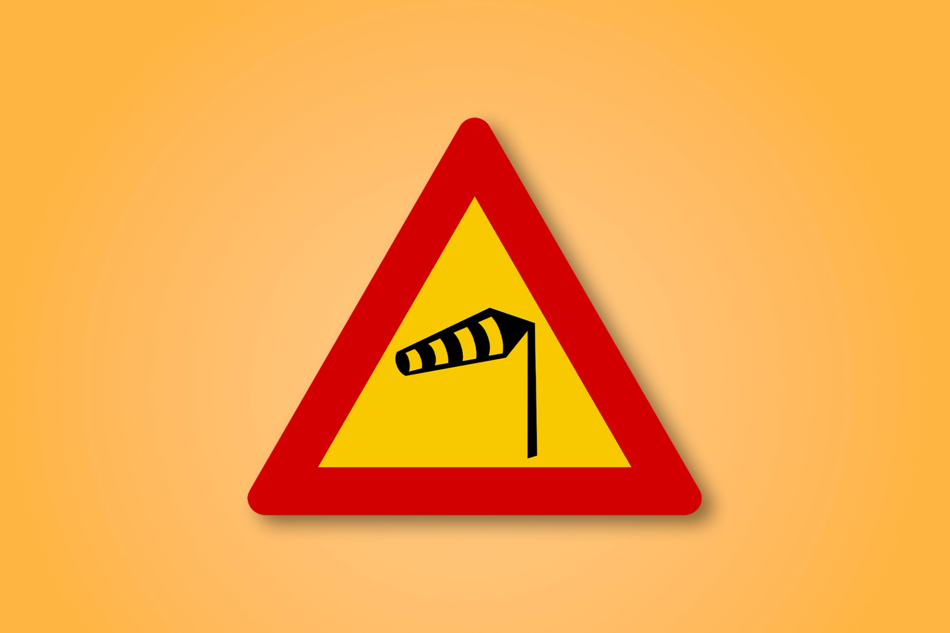 Red and yellow triangle road sign with a wind in the middle. This road sign means Crosswinds